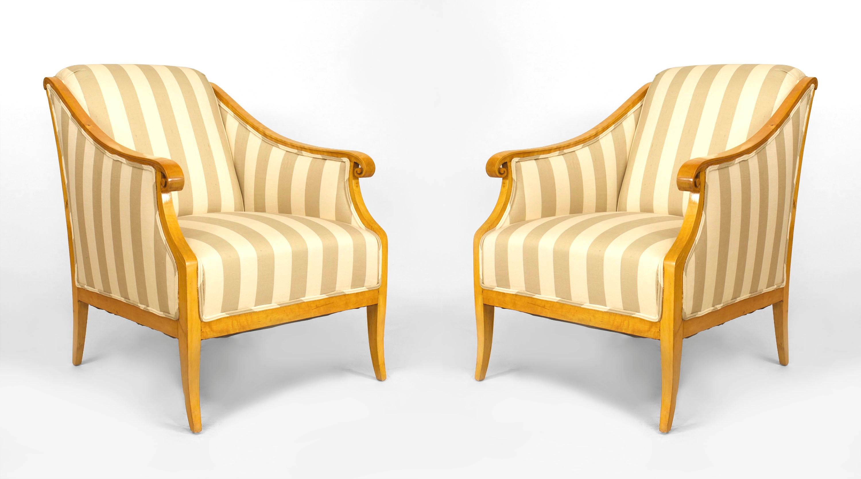 Pair of maple nineteenth century Swedish Biedermeier bergeres each featuring a sleigh back design, scroll front arms, and striped beige upholstery.
