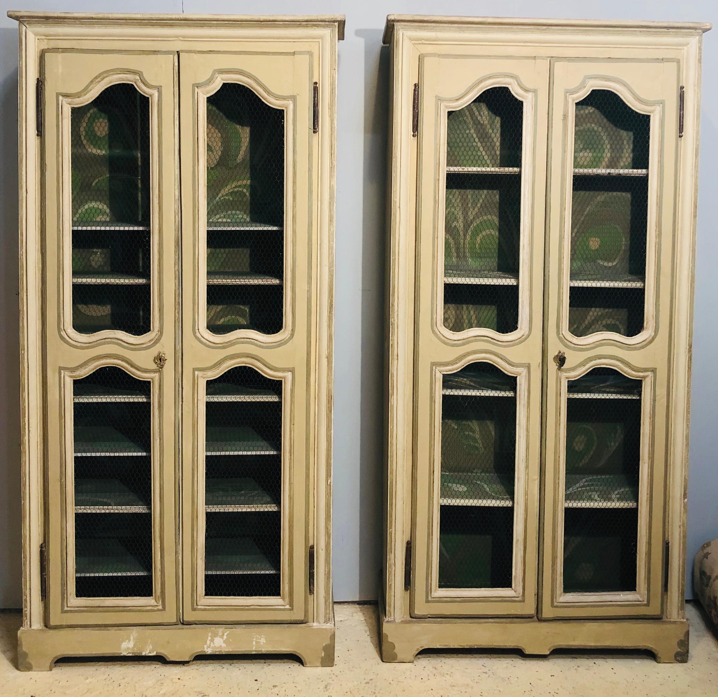 Pair of continental bookcase cabinets. Painted in an olive green with white and gray design this magnificent pair of bookcase cabinets are simply worthy of any home setting. The pair sit in their original splendor with a fully painted interior and