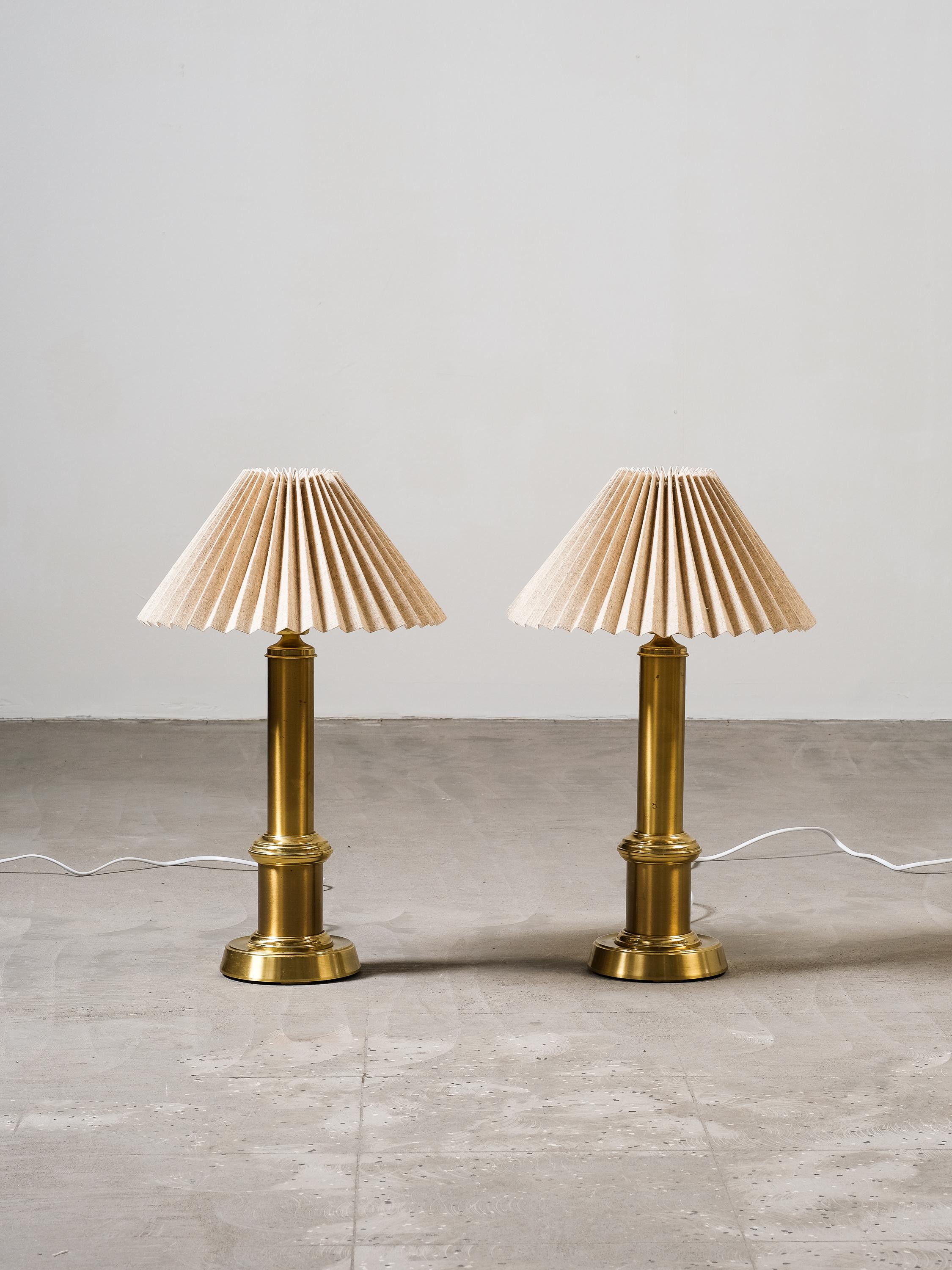 This pair of Swedish brass table lamps from the 1960s by Ewå Värnamo is a stunning addition to any room. The pleated fabric shades provide a cozy and warm glow, creating a welcoming atmosphere. With sleek design and high-quality materials, they add