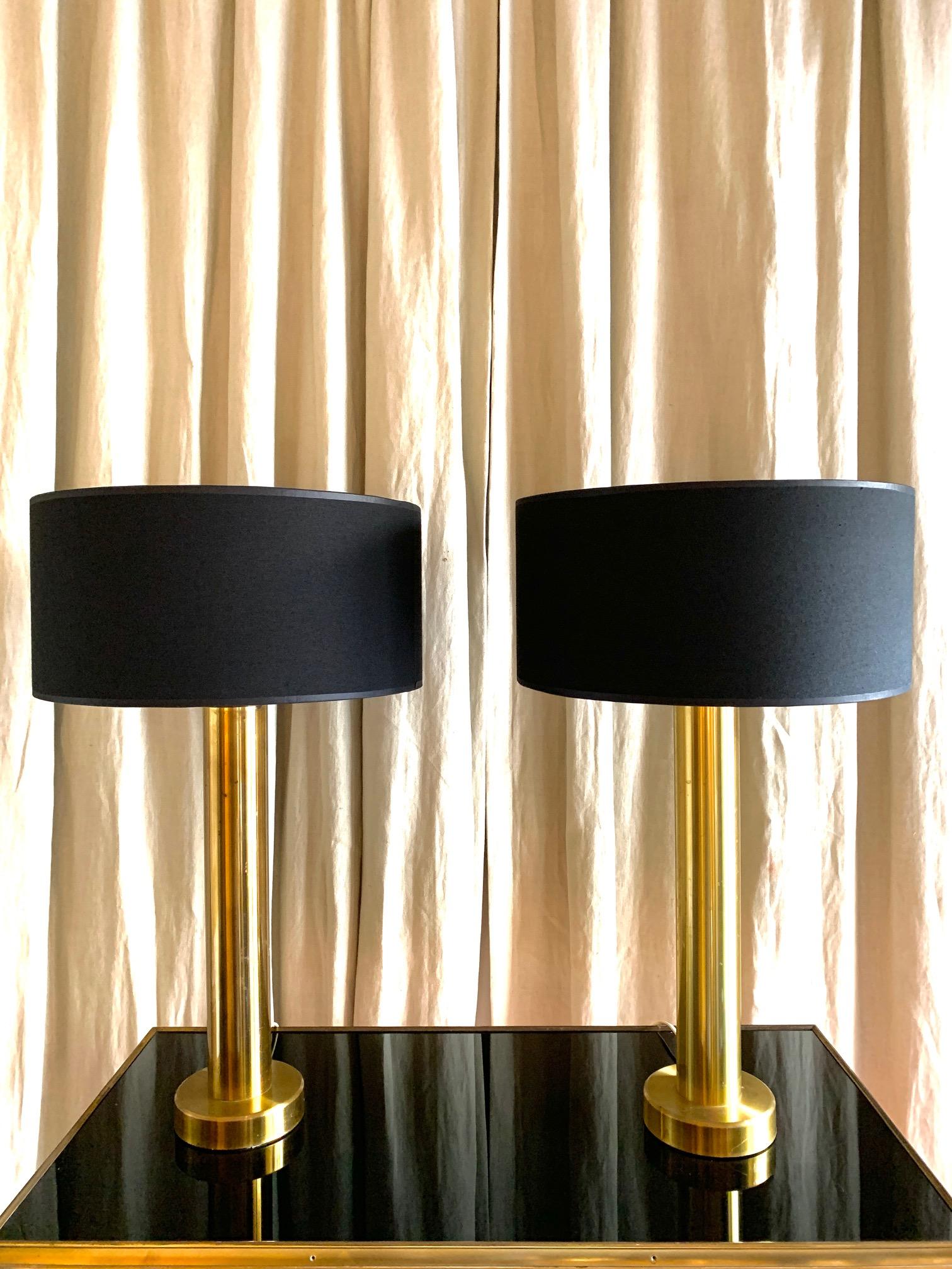 A pair of table lamps, in the shape of a column in full brass, Swedish design from the 1970s, The shades in black with gold interior, each one measuring 15 cm high x 30 cm diameter.