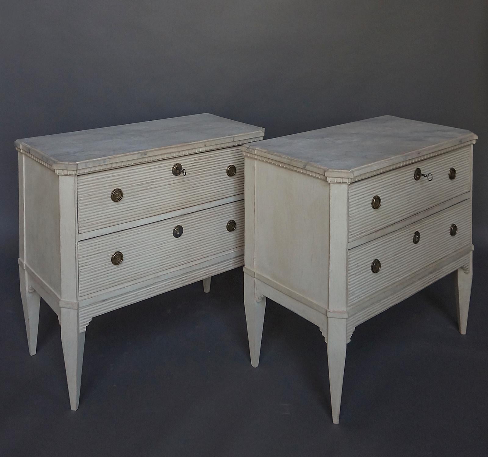 Pair of Swedish commodes, circa 1880, having horizontal reeding on their drawers and aprons. Their shaped tops have dental detail and marbleized surfaces. Canted corner posts extend into tapered square legs. These would be perfect on either side of