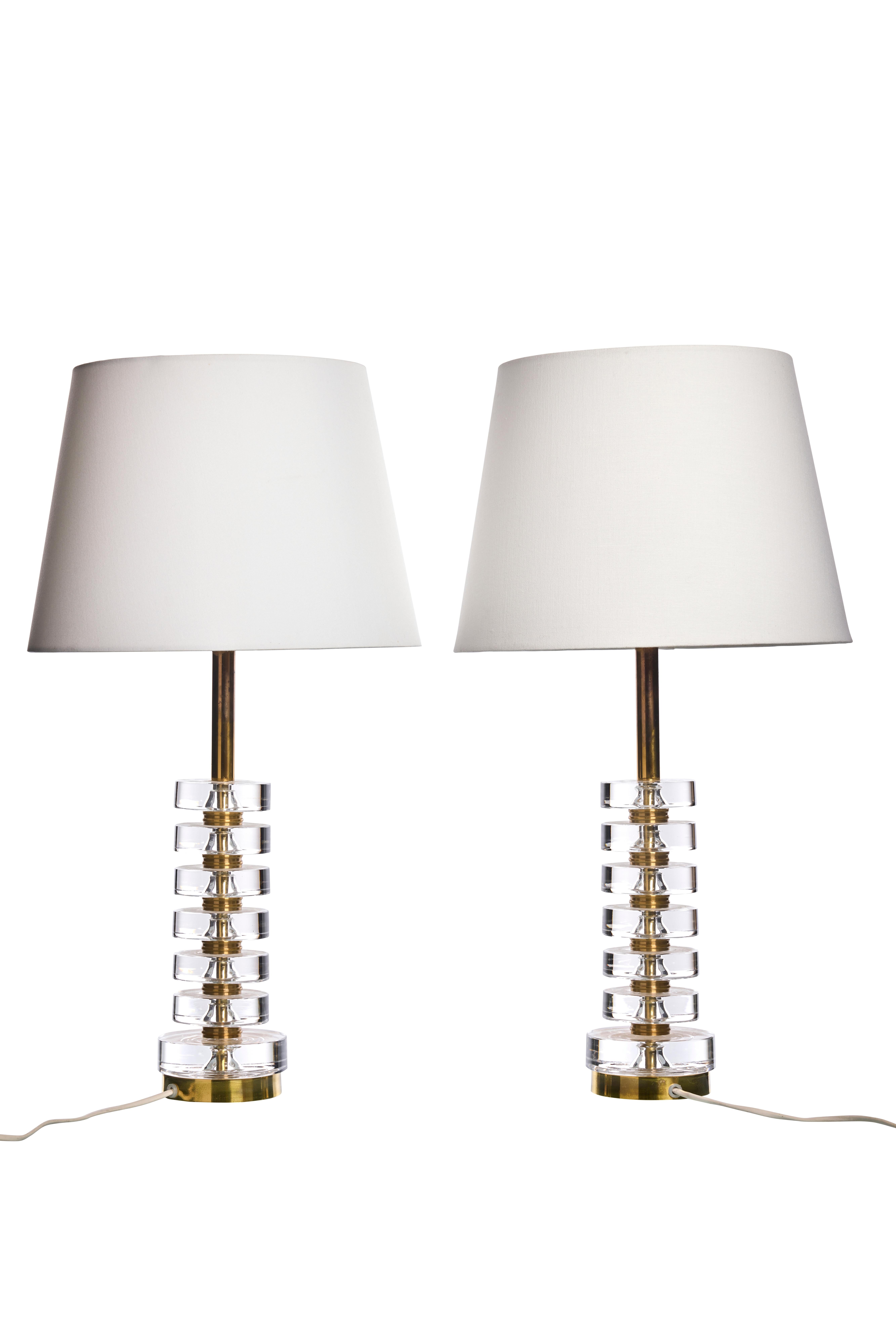 A pair of elegant table lamps by Carl Fagerlund for Orrefors. The lamps beautiful design makes them suitable for all interior styles.
The lamps consist of six discs of clear crystal glass, separated by solid brass discs.

We have four of this table