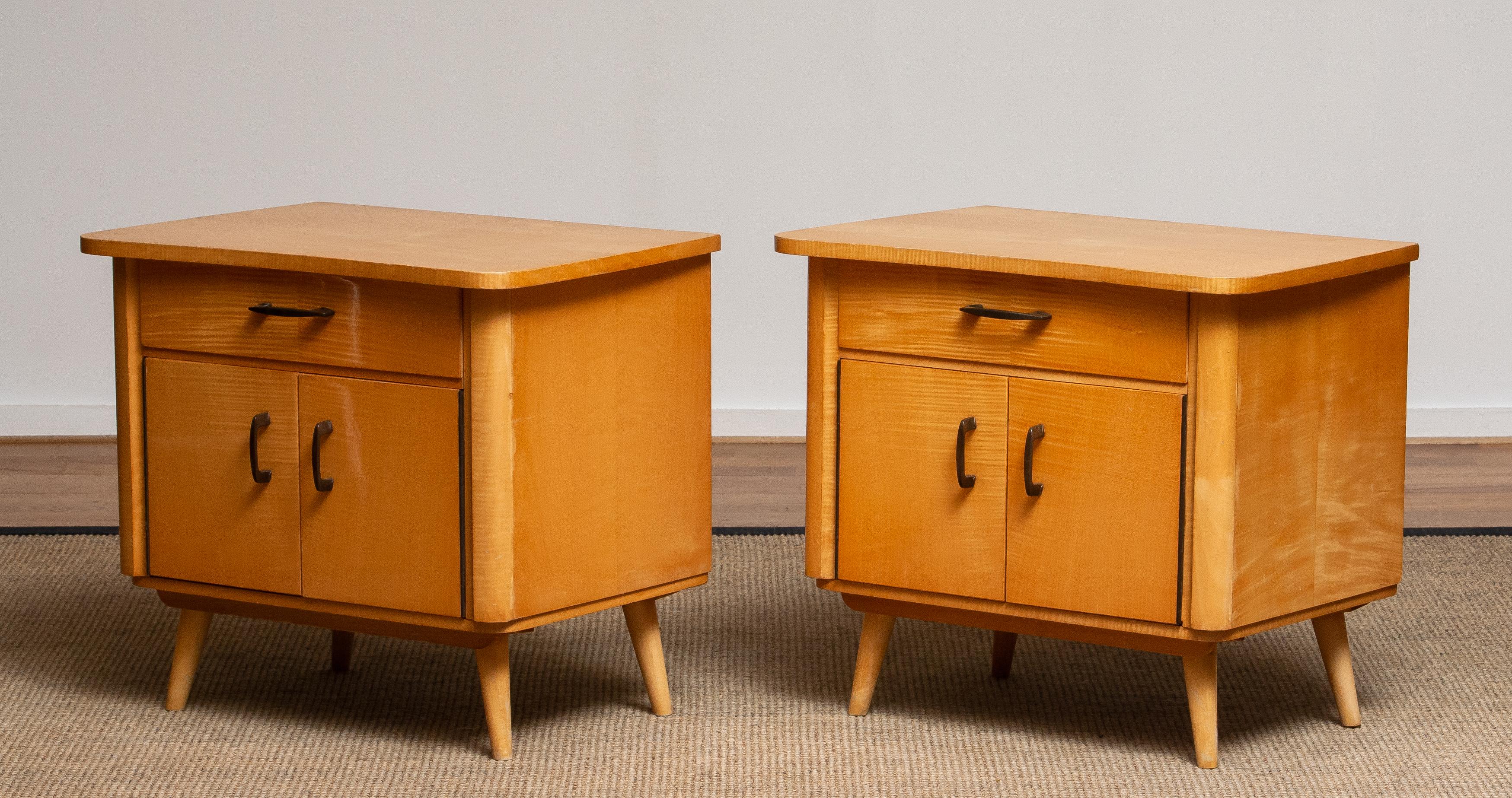 Charming pair of mid-century modern nightstands crafted in Sweden from warm-toned elm wood. Each piece features a clean, functional design with a single drawer above a double-door cabinet, offering both style and practical storage. The cabinets rest