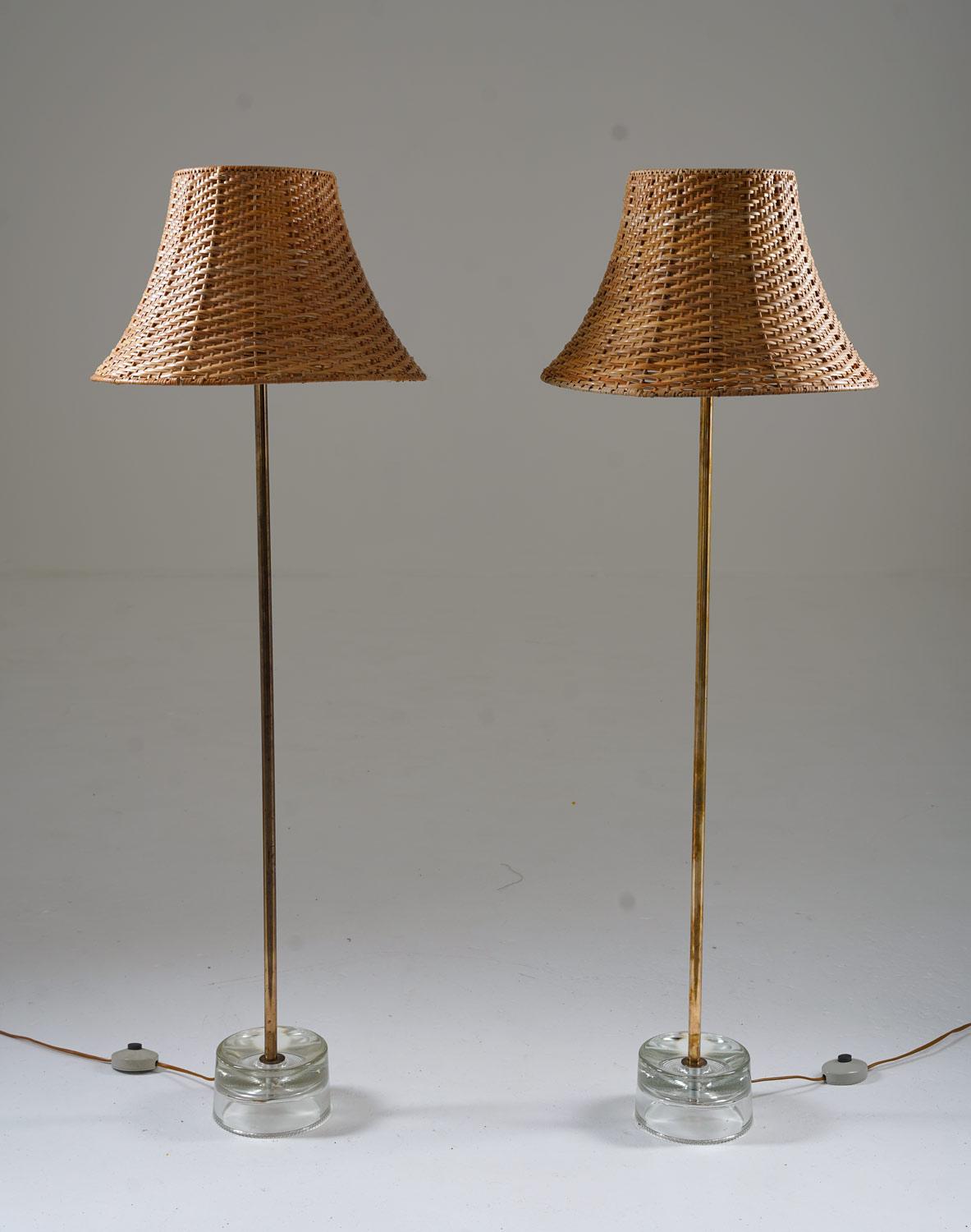 This rare set of two midcentury floor lamps was manufactured in the 1960s by Stilarmatur Tranås in Sweden. The lamps consist of a clear glass foot, underneath a stem in brass. They come with gorgeous vintage shades in rattan.

Condition: Very good