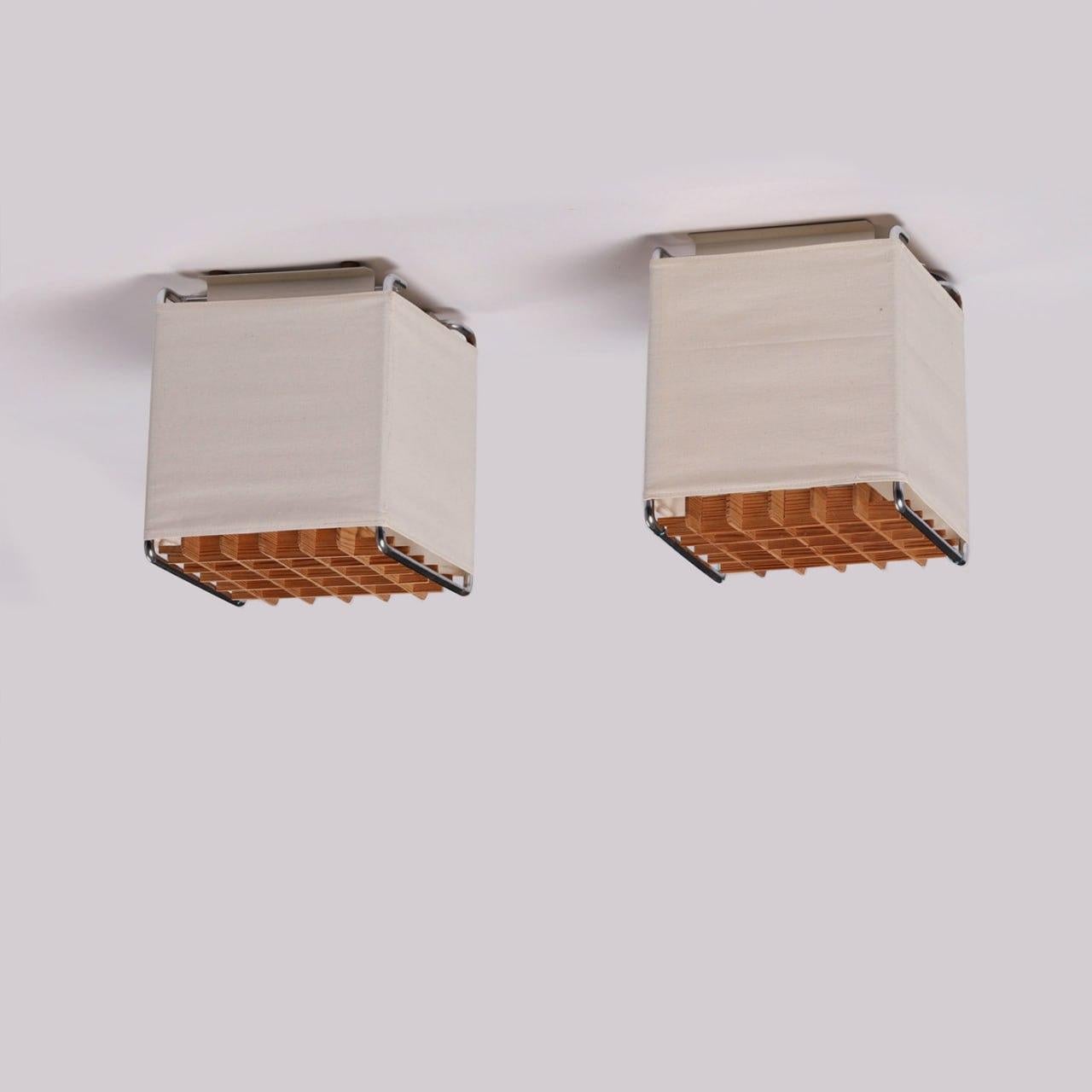 Pair of Swedish mid-century modern flush-mount ceiling lamps, produced in the 1970s. Metal frame, original semi-transparent fabric, removable wooden grid. Each lamp is equipped for one light bulb. In good original condition, wear consistent with