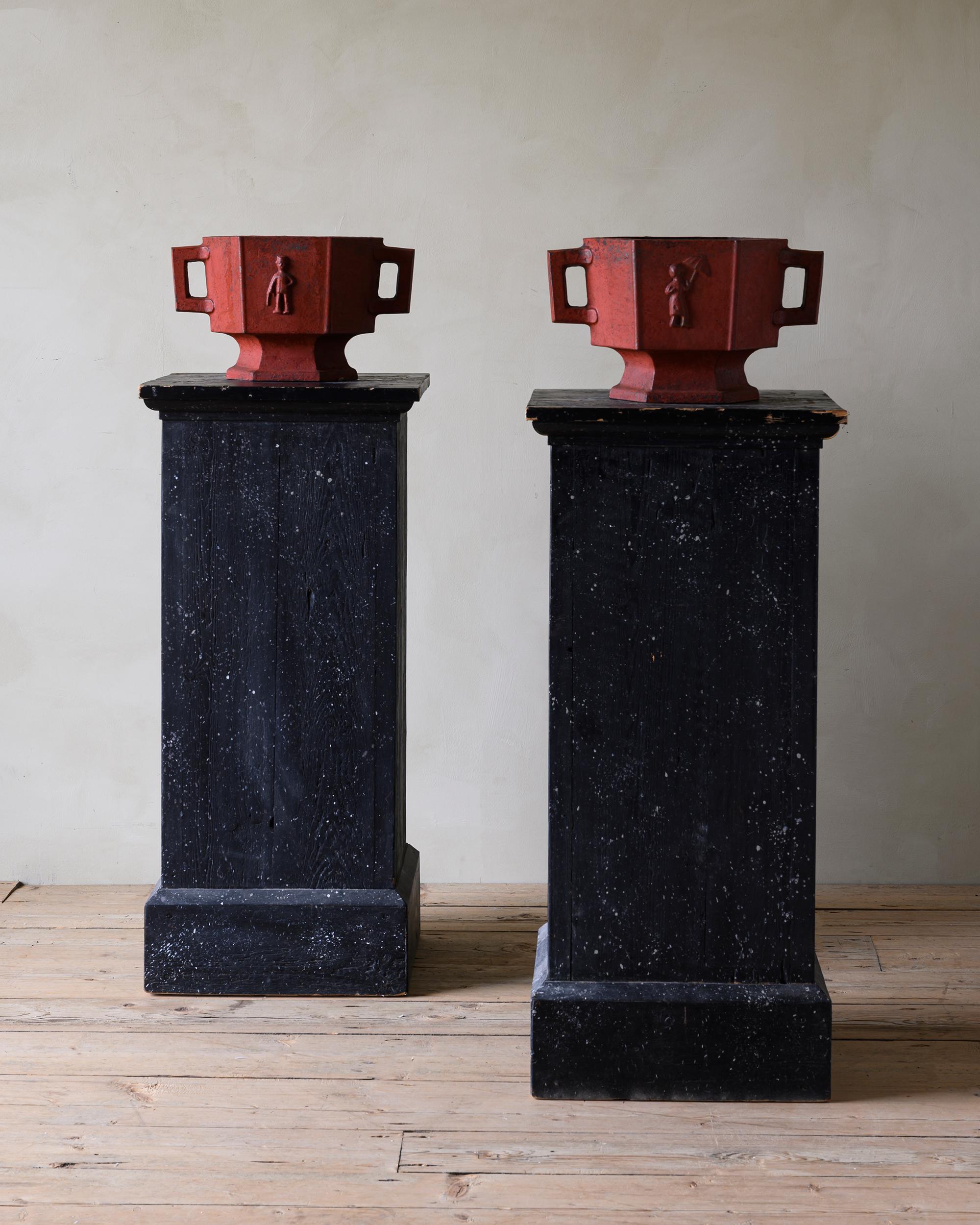 Fine pair of Swedish Grace (art deco) cast iron urns or planters depicting a man with a walking stick and a woman with an umbrella. In their original red finish with great patination. 1930s Sweden.