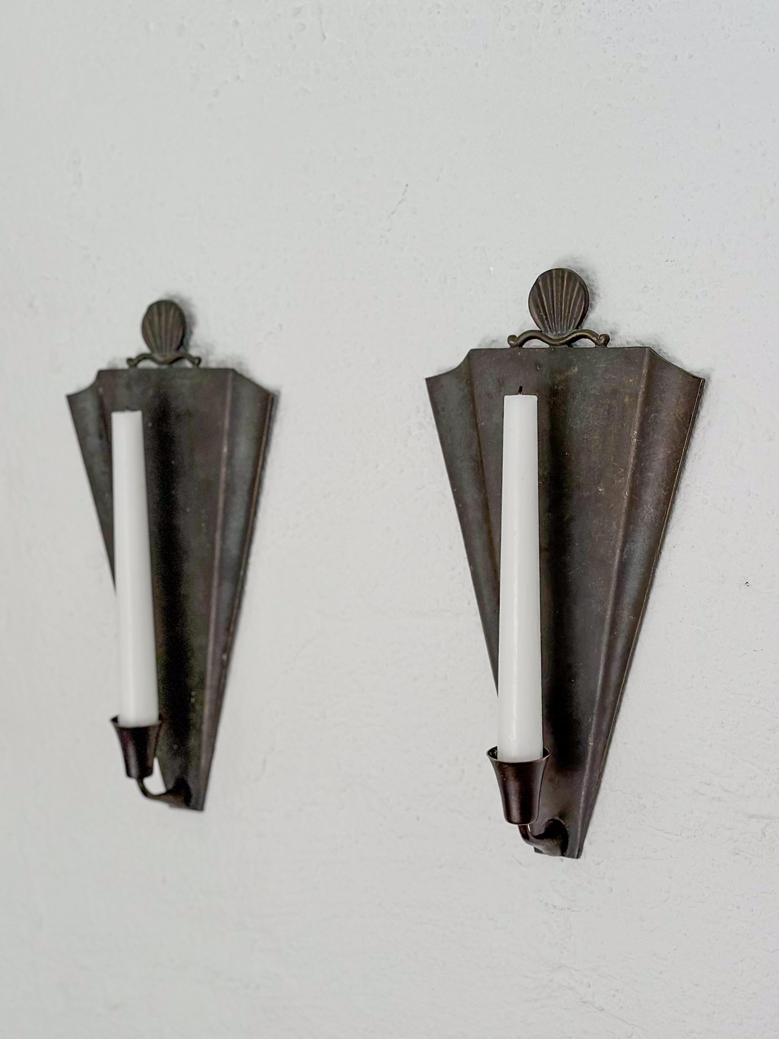 Rare pair of Swedish Grace shield shaped patinated bronze candle sconces made by Ystad Metall in the late 1920s or 1930s. Simple, elegant design with sea shell decor and nice weight. Fits regular chandelier or antique candles. Marked 