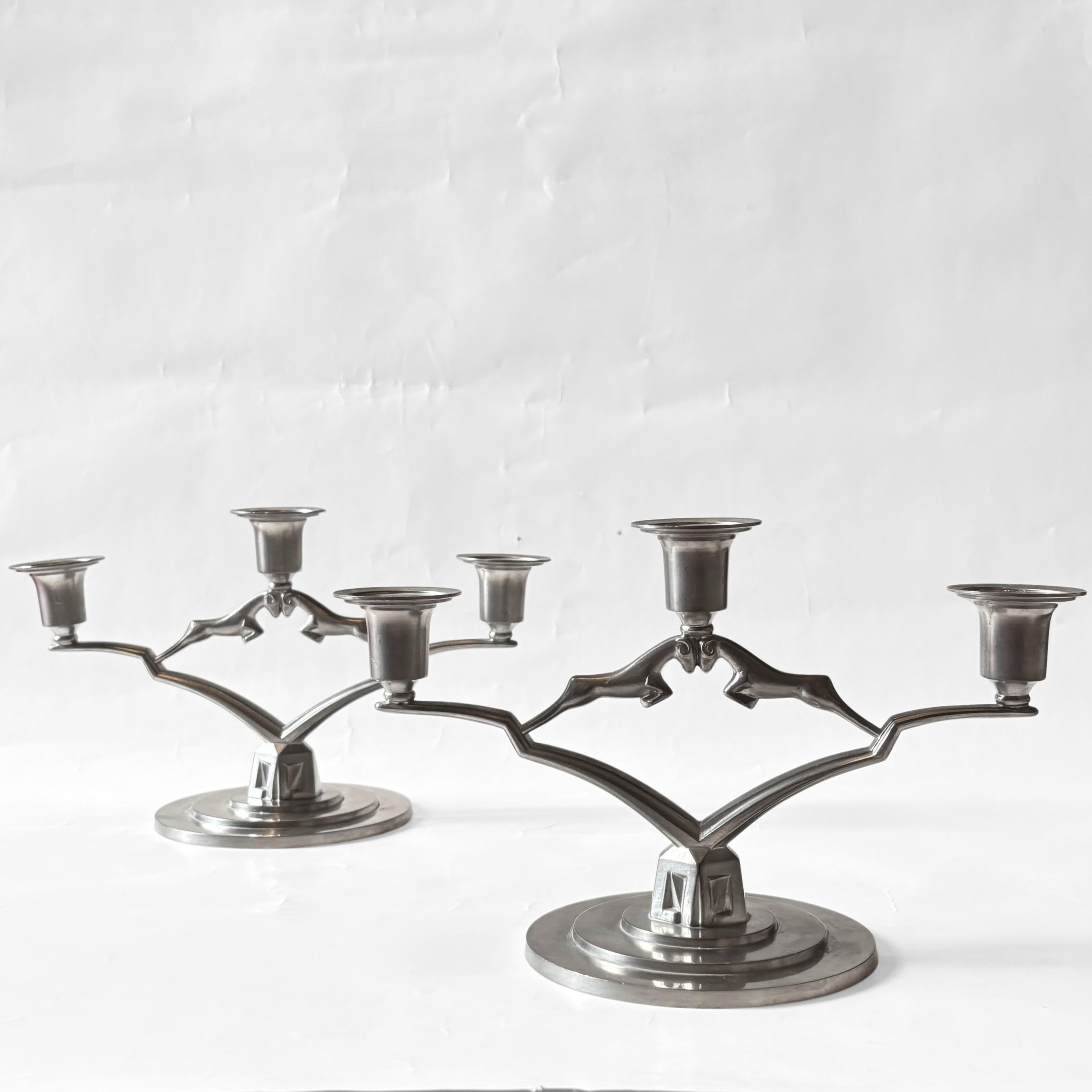 A striking pair of neoclassical Swedish Grace candelabra designed by Thorild Knutson (1896–1985), crafted in Gränna, Sweden. Each piece features a circular stepped base and three candle holders, beautifully adorned with a pair of stylized antelopes
