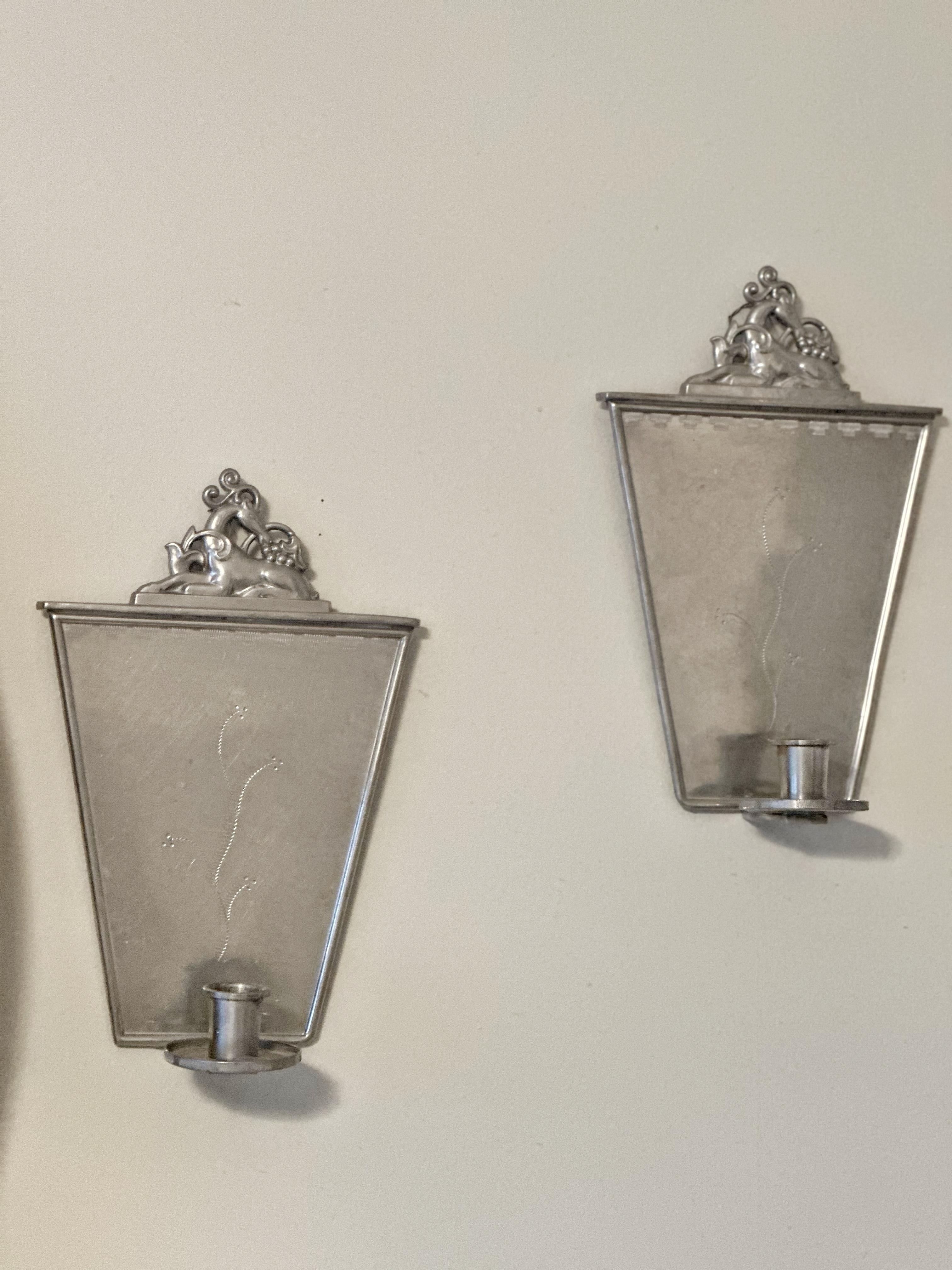 Pair of Swedish Grace Pewter Walls Candlesticks by Carl Gustav Hallberg, Stockholm. Keystone shaped backplate with a vine motif.. The crown depicts a reclining deer surrounded by plants. Each wallstick has a pewter candle holder. 
Made by Elis Bergh