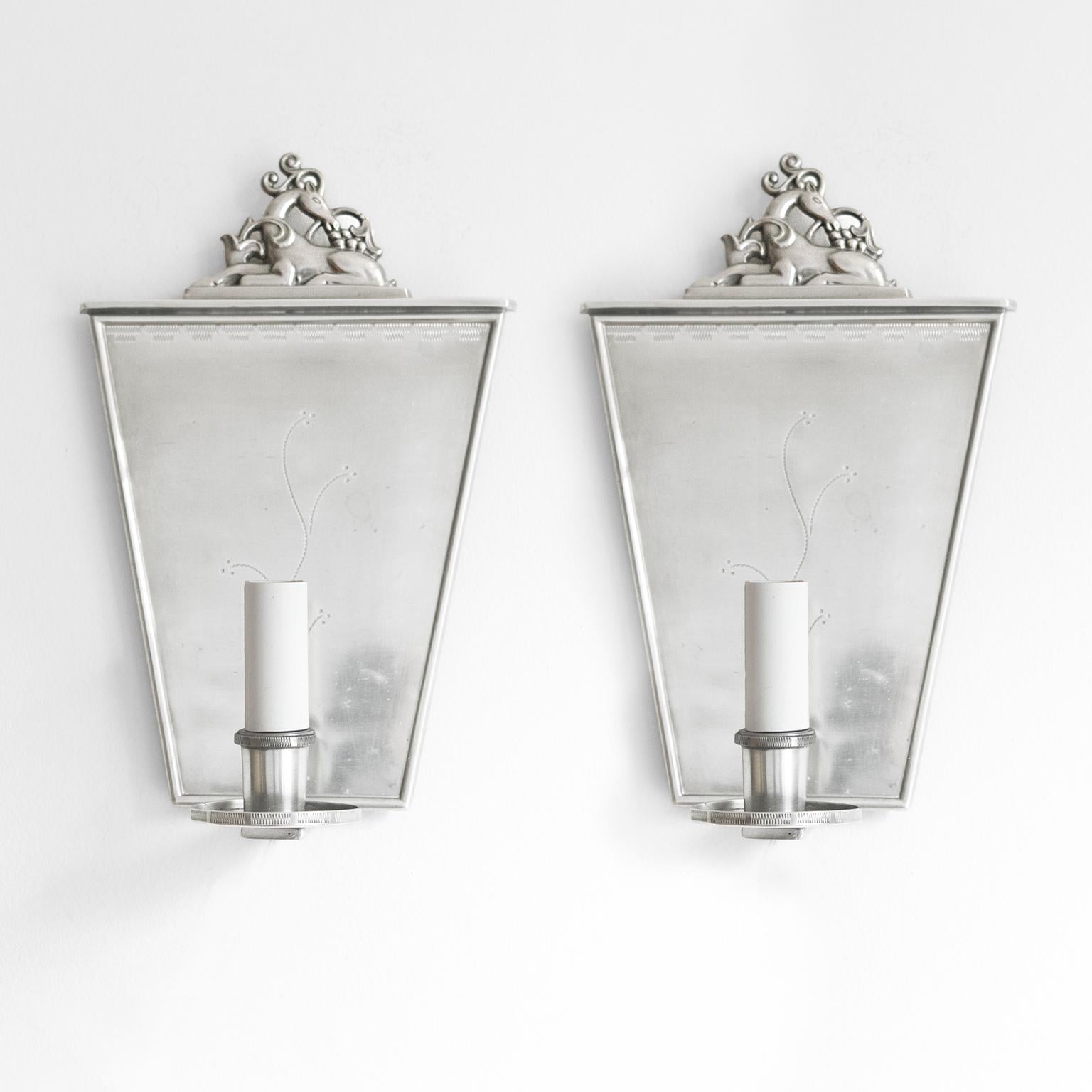 Pair of Swedish Grace polished pewter sconces by, C.G. Hallberg, Stockholm. The keystone shaped backplate is finely hand detail with a vine motif.. The crown depicts a reclining deer surrounded by plants. Each sconces has a single candle with a