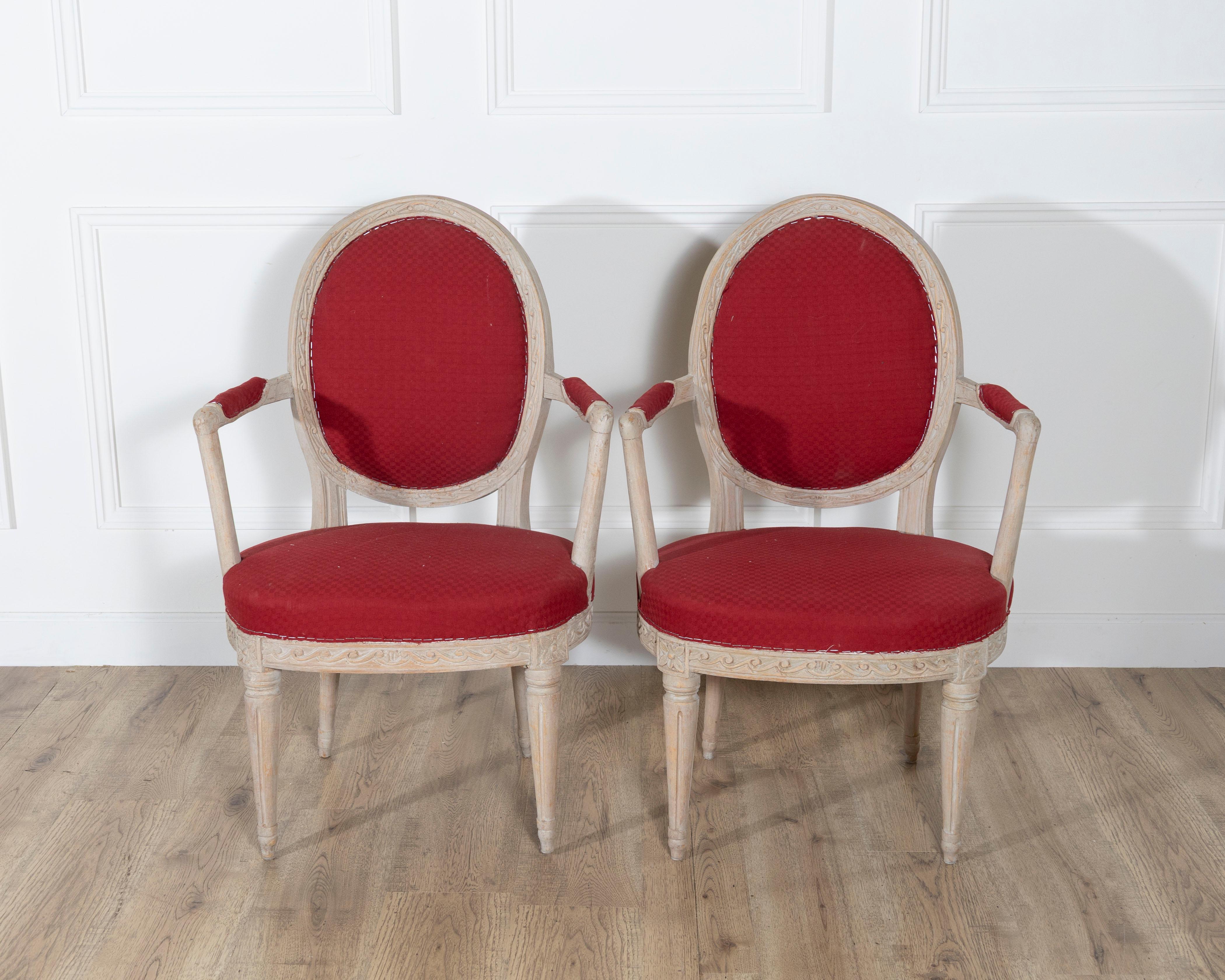 Refined pair of Swedish Gustavian armchairs, circa 1820, retaining their original pale painted finish and classic neoclassical form. Each chair features an oval upholstered backrest, gracefully curved arms, and fluted legs adorned with carved