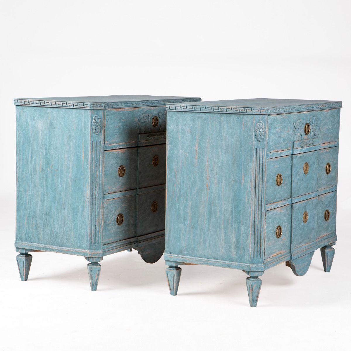 Elegant pair of Gustavian-style breakfront commodes from Sweden, circa 1840–1860.

Each is painted in a light blue tone with a charming patina.
Below the top runs a finely carved à la grec frieze.
The corpus has three drawers — the upper decorated