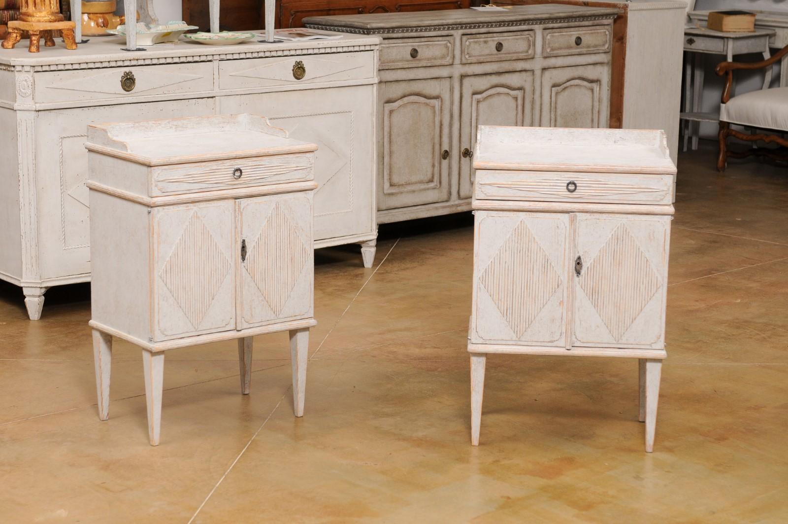 A pair of Swedish Gustavian style painted wood bedside tables from the early 20th century, with reeded diamond motifs. Created in Sweden during the first quarter of the 20th century, each of this pair of nightstand tables features a rectangular top