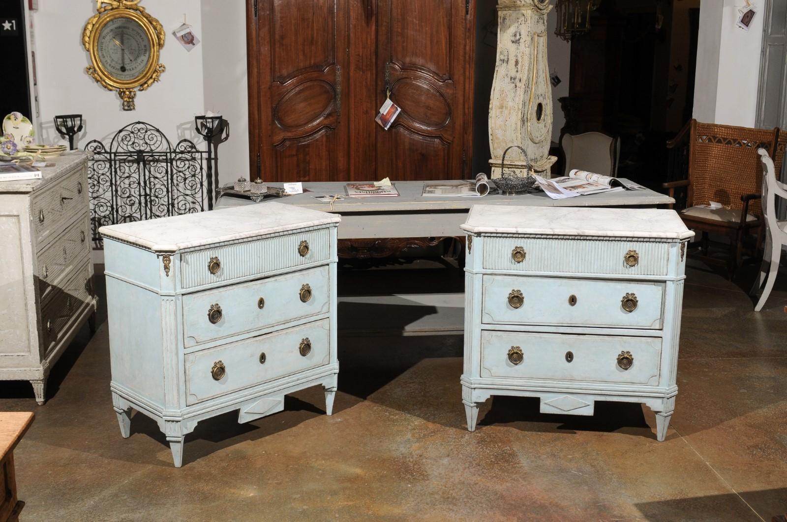A pair of Swedish Gustavian style light blue painted wood chests from the 19th century, with faux marble tops, reeded accents and canted side posts. Born in Sweden during the 19th century, each of this exquisite pair of chests features a marbleized