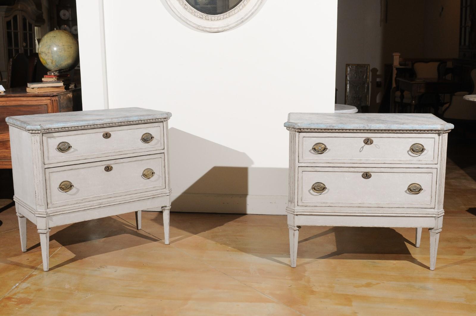 A pair of Swedish Gustavian style painted two-drawer chests from the 19th century, with marbleized tops and fluted motifs. Created in Sweden during the 19th century, each of this pair of Gustavian style chests features a faux marble painted top with