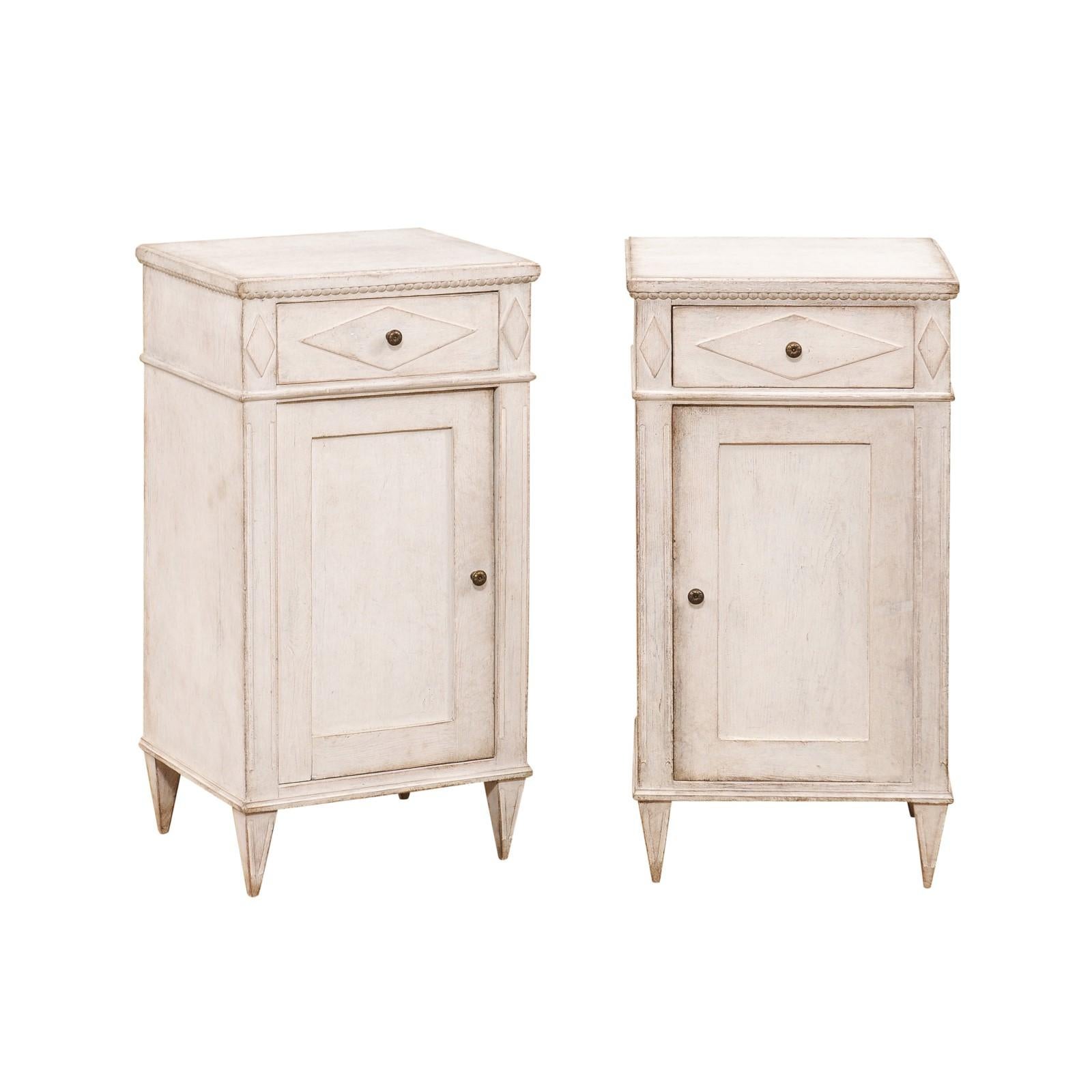 A pair of Swedish Gustavian style painted wood bedside cabinets from the 19th century, with carved diamond motifs, beaded frieze, single drawer over single door. Created in Sweden during the 19th century, each of this pair of Gustavian style bedside