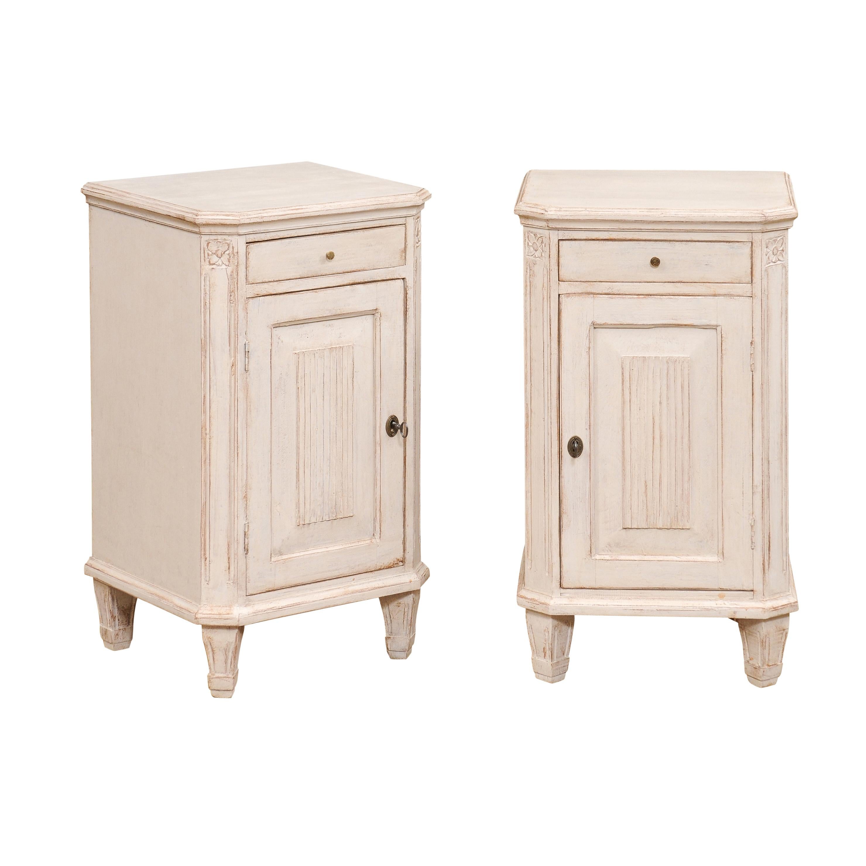 A pair of Swedish Gustavian style painted wood nightstand tables from the 19th century with single drawers and doors, carved fluted motifs, canted side posts, carved rosettes. Add a touch of Swedish Gustavian elegance to your bedroom with this pair