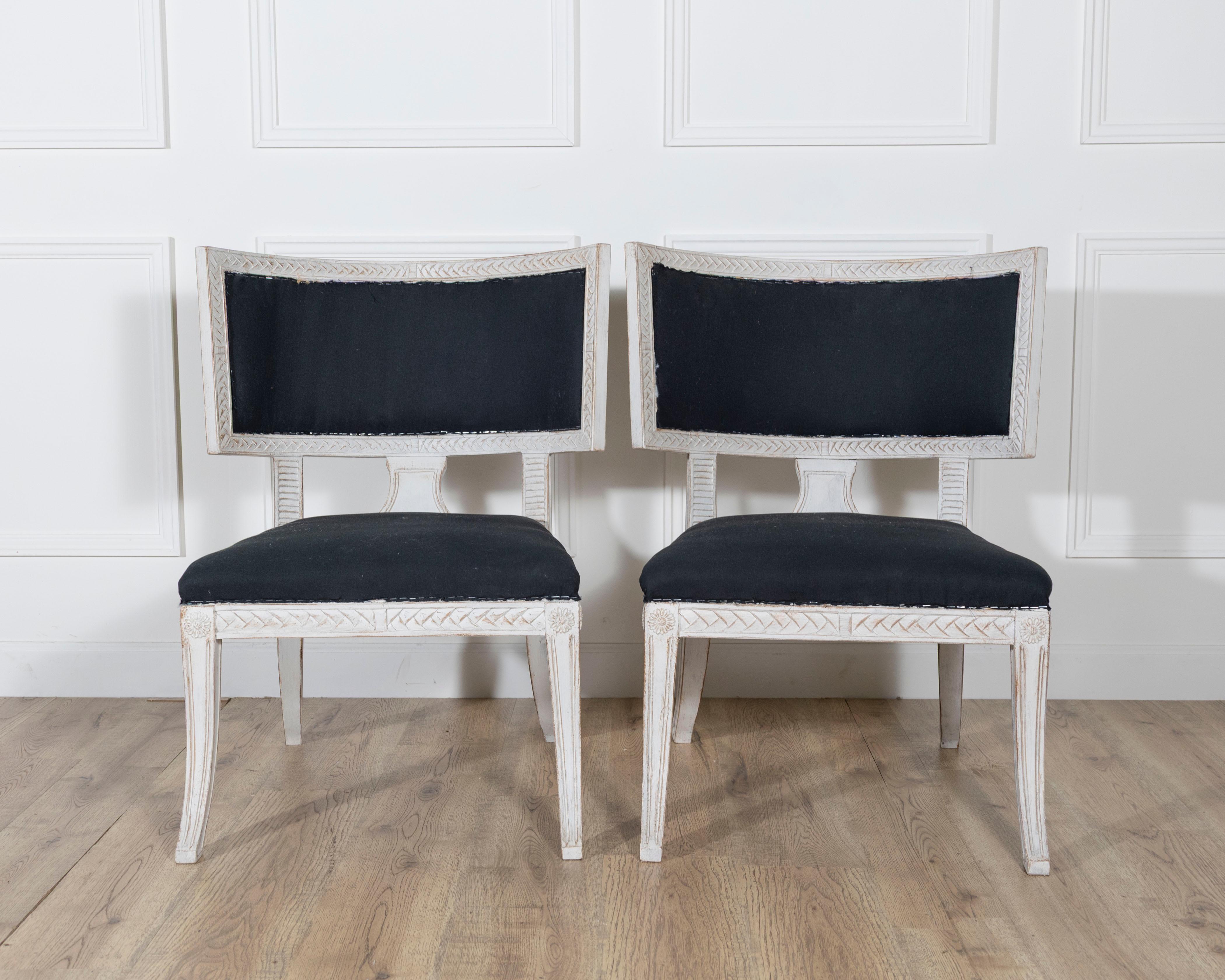 Une paire raffinée de chaises suédoises de style gustavien, qui se distinguent par leur forme néoclassique et leur élégance discrète. Les cadres sont sculptés de délicats motifs de feuilles de laurier et de bandes transversales, et sont recouverts
