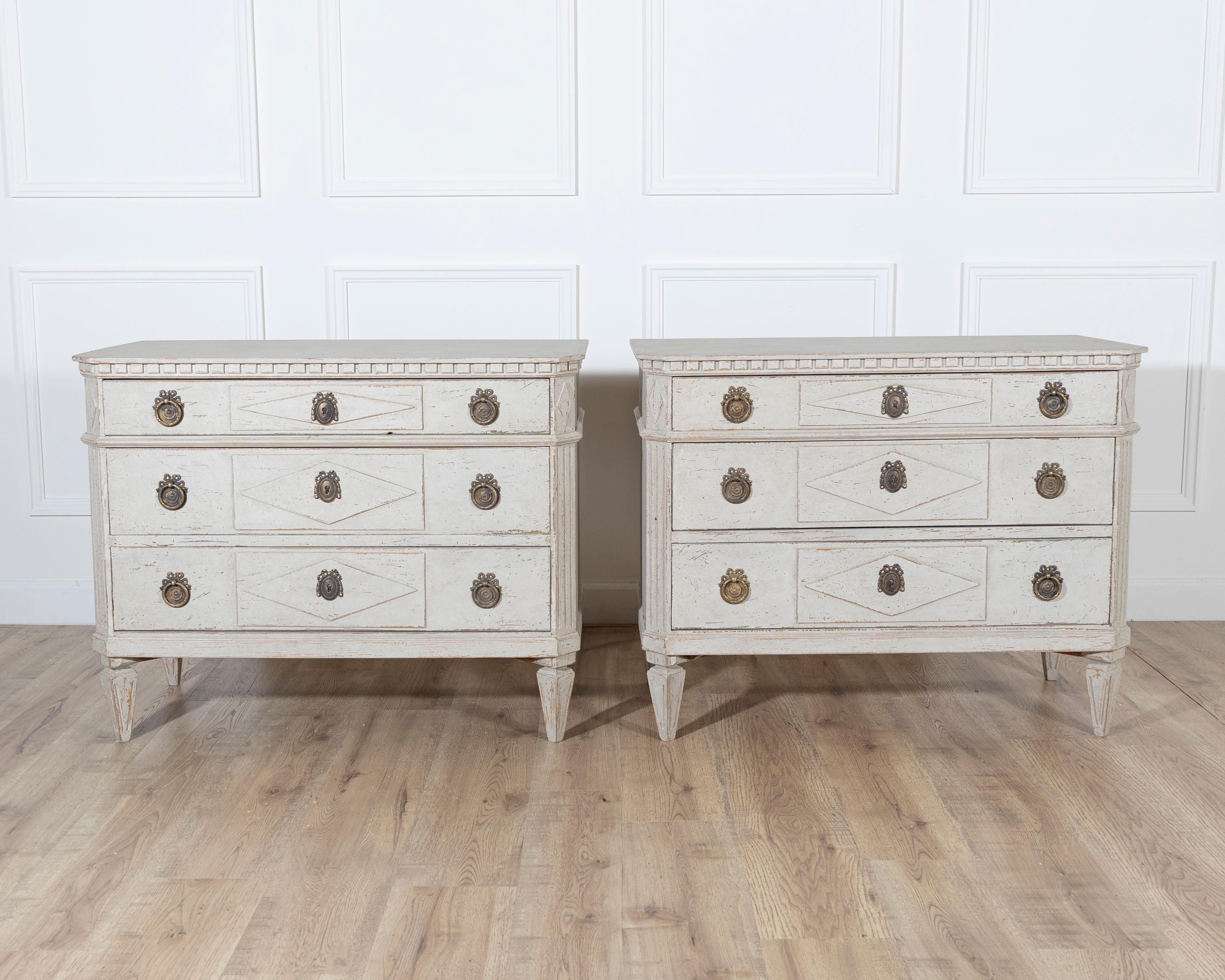 A charming pair of Swedish Gustavian-style painted chests of drawers, dating to the early 20th century, inspired by the neoclassical tradition that defined late 18th-century Scandinavian design. Each chest features three drawers, framed with