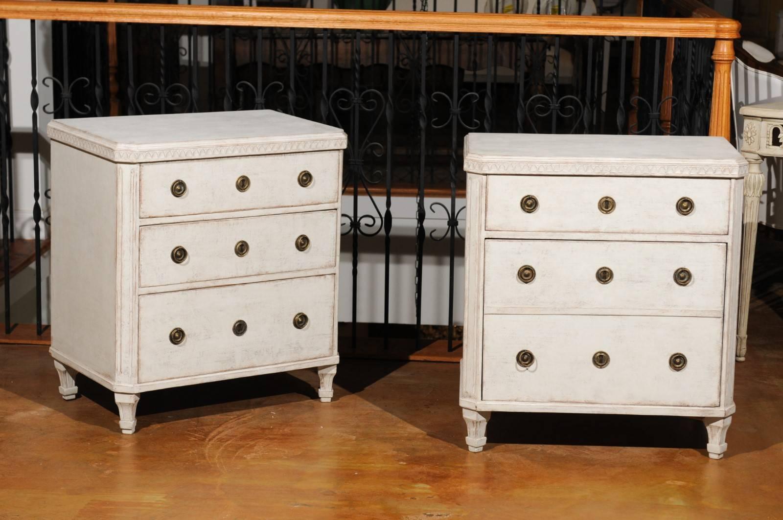 A pair of Swedish Gustavian style painted wood chests from the early 20th century, with carved moldings, drawers and doors. Each of this unusual pair of Swedish chests features a slightly raised rectangular top with canted corners in the front,