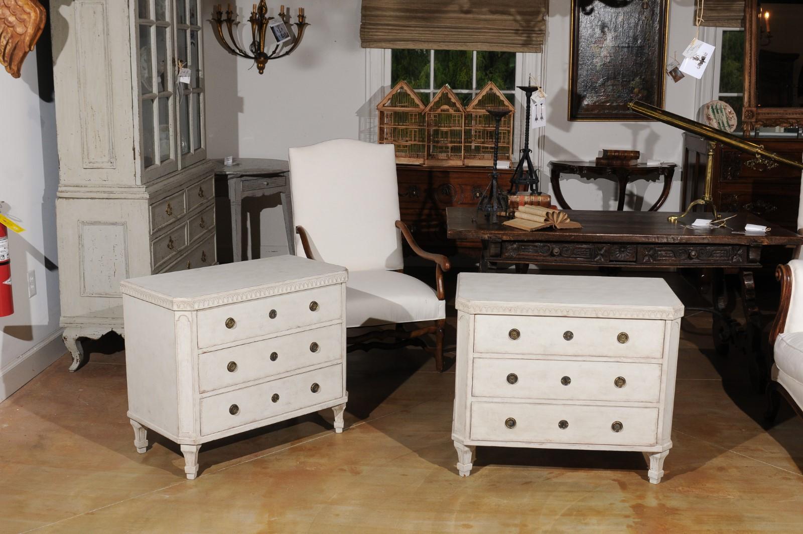 A pair of Swedish Gustavian style painted wood three-drawer commodes from the late 19th century, with canted side posts and tapered feet. Born in Sweden during the later years of the 19th century, each of this pair of painted chests features a