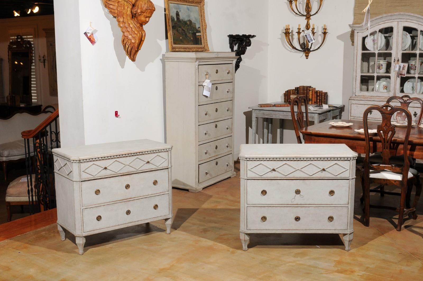 A pair of Swedish Gustavian style painted wood three-drawer chests from the 19th century, with dentil molding and diamond motifs. Created in Sweden during the 19th century, each of this pair of Gustavian style chests features a rectangular top with
