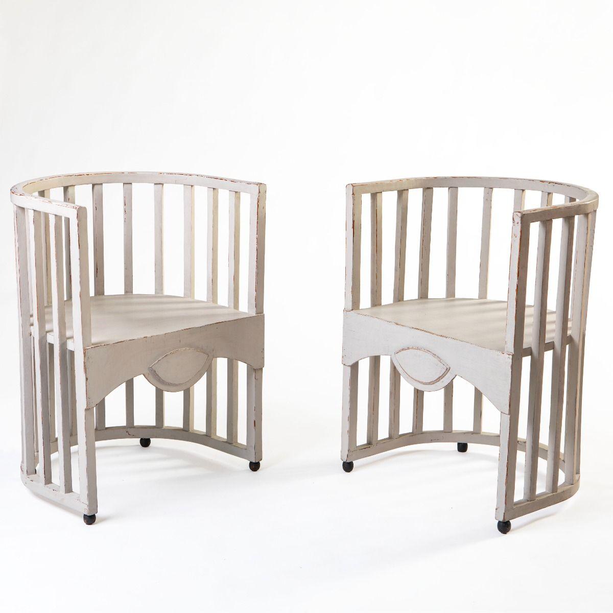A pair of Swedish Jugend chairs, crafted from painted pine in a soft grey-white hue with contrasting black feet. The design is clean and understated, featuring semicircular seats, gently curved backrests, and vertical slats.

The original striped
