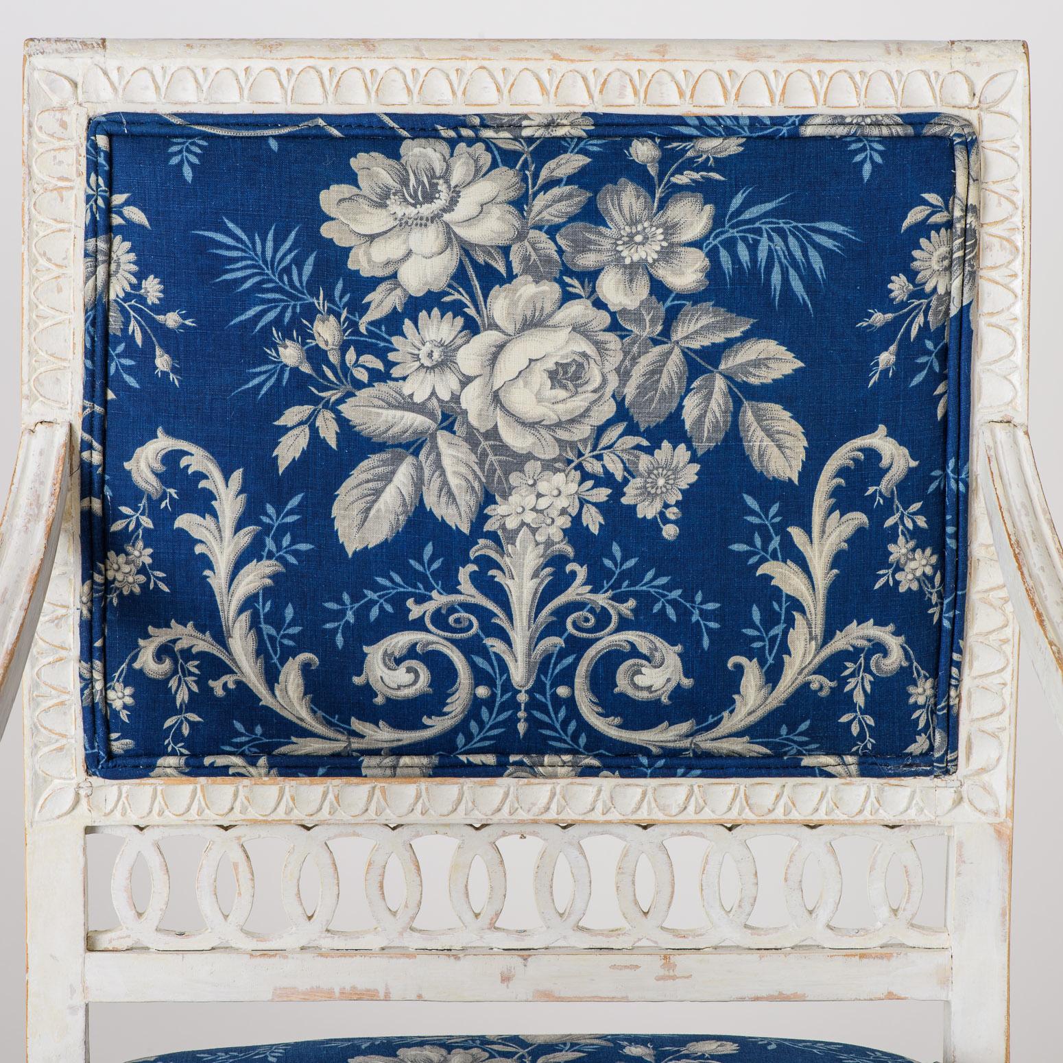 An attractive pair of armchairs with many features of the Gustavian style in Stockholm, including an openwork cut-out design at the backs, delicate carvings on the aprons, and a circle of acanthus leaf carvings on the front legs. They are covered