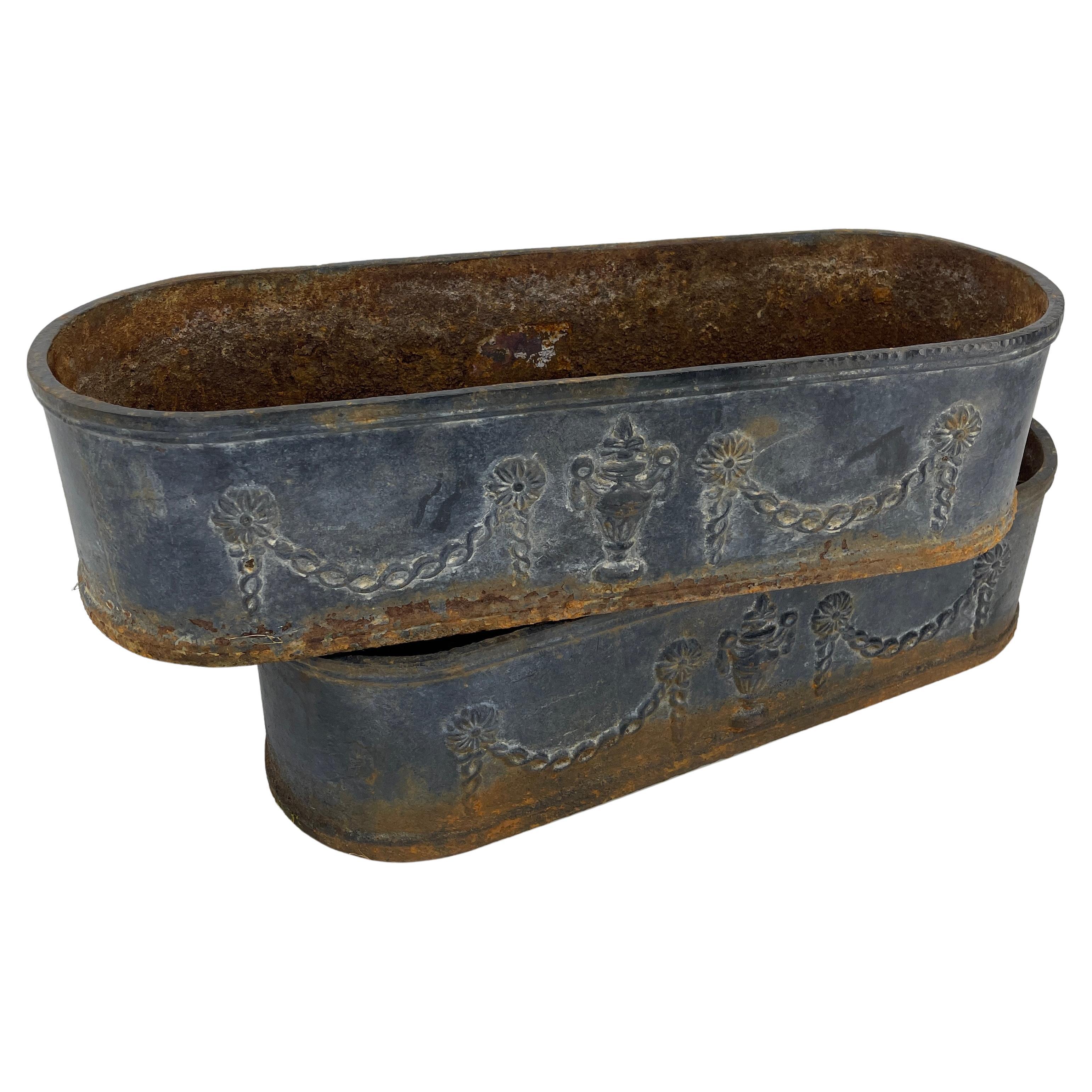 19th century Pair of cast iron swedish oval planters with original blue paint.

Weathered metal finish with incredible old world patina and the original petroleum-blue paint. Lovely Louis Seize garland and urn details on the sides. Single drain