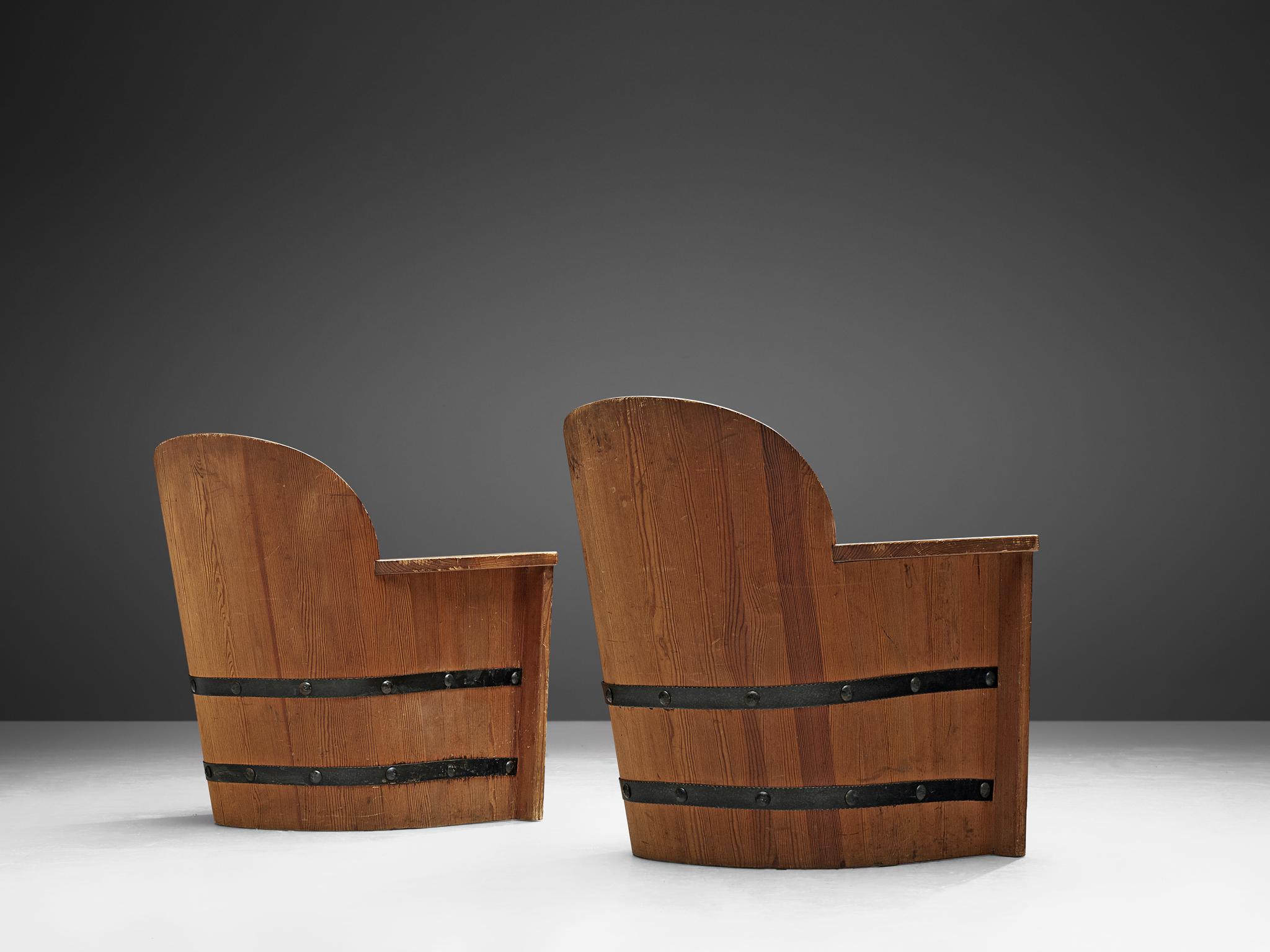 Pair of lounge chairs, pine, iron, Sweden, 1930s-1940s

Pair of armchairs made of stained pine with forged iron fittings. The chairs resemble the look of wooden barrels, giving it an artisan look. This is mainly achieved by the forged iron fitting