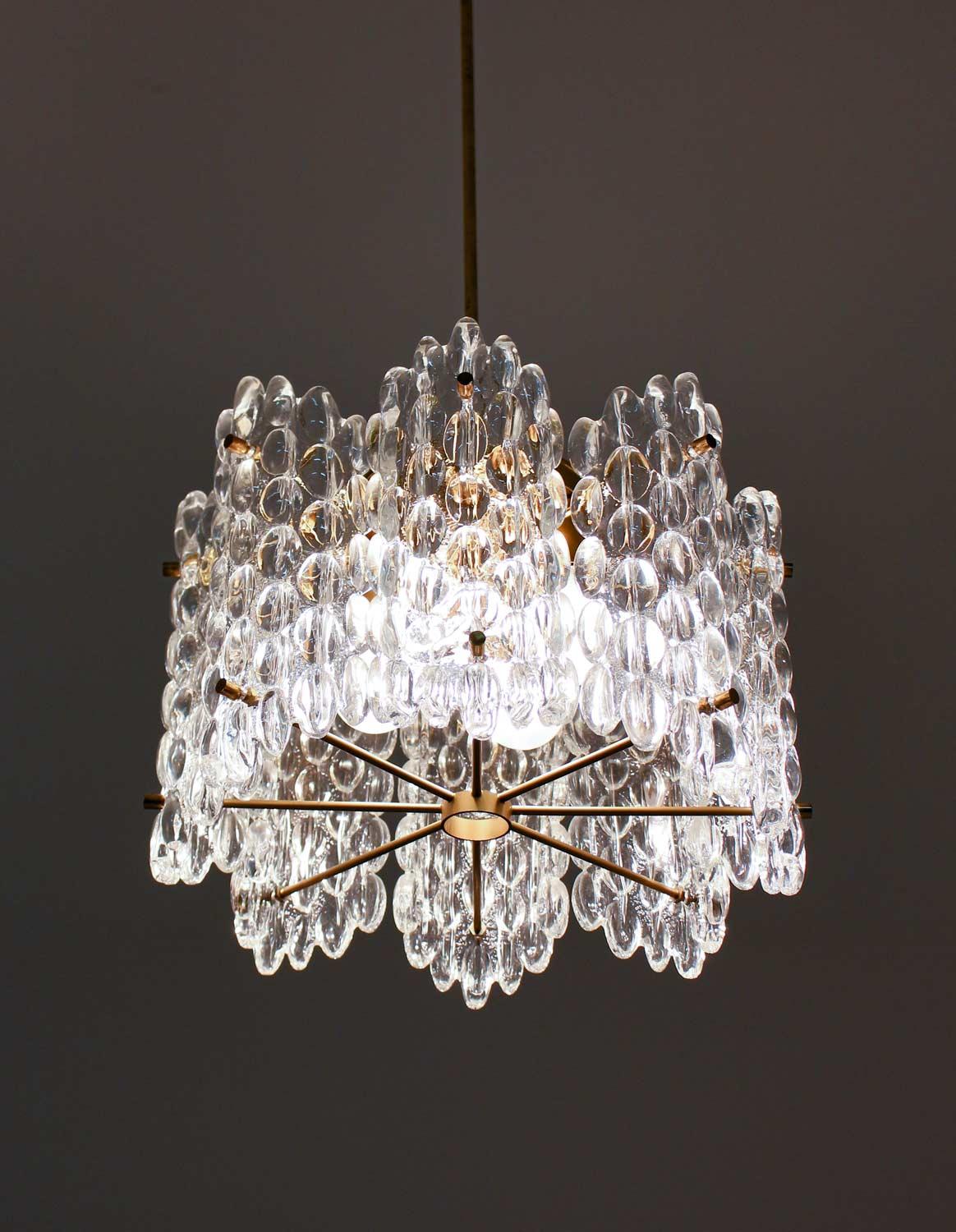 Impressive chandeliers in crystal glass and brass. The lamps feature six glass blocks separated by two brass dividers. Each lamp has four-light sources.

Condition: Very good, age related wear on the brass.
 