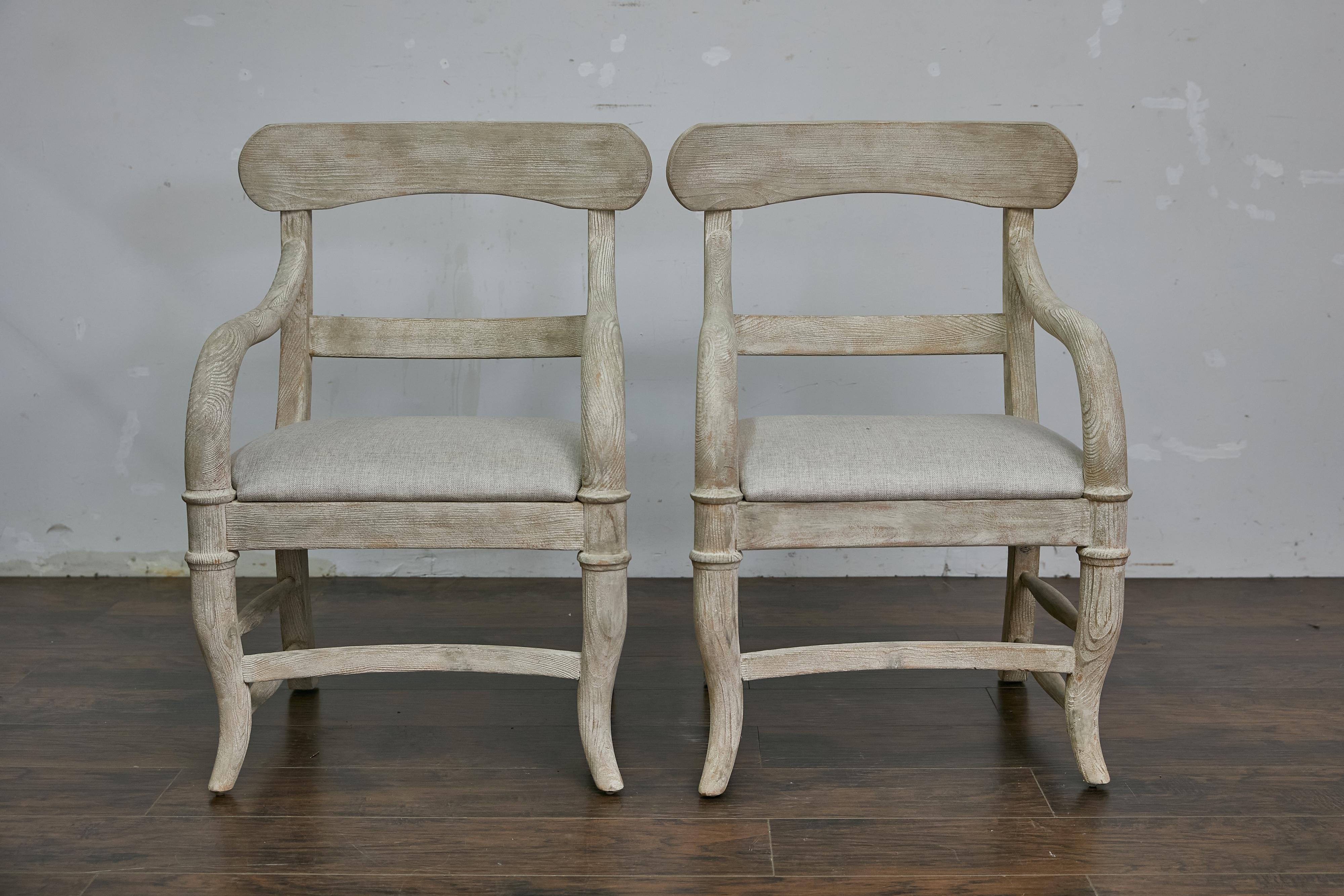 Coppia di poltrone svedesi in legno verniciato di bianco del periodo del Medioevo, con schienali aperti, sedute imbottite su misura, gambe ricurve e barelle laterali. Questa coppia di poltrone svedesi del periodo Midcentury cattura perfettamente