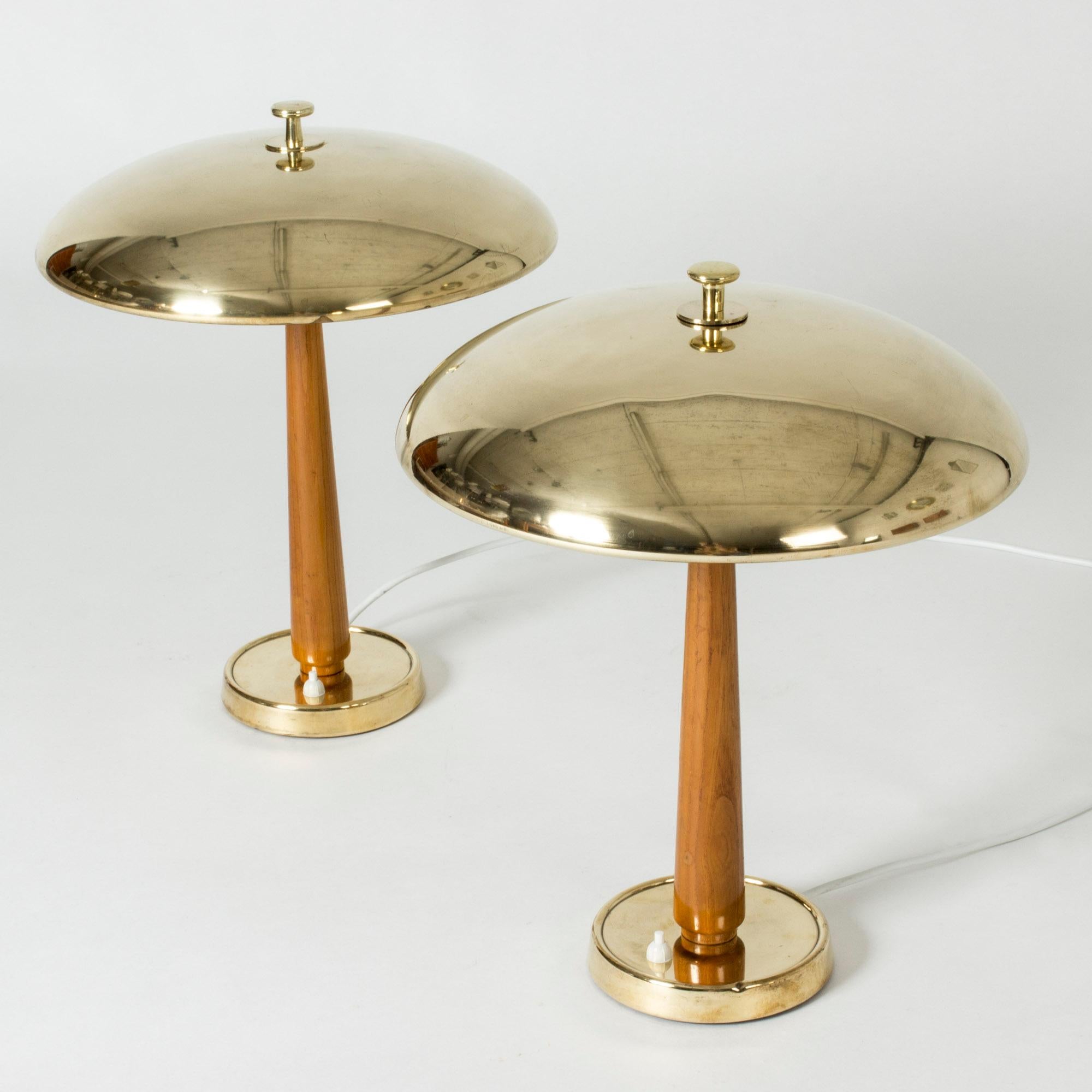 Pair of amazing table lamps from NK, with wide, streamlined brass shades. Cool decorative knobs on the tops. Smooth wooden handles and brass bases. Beautiful combination of materials. Price is for the pair.
