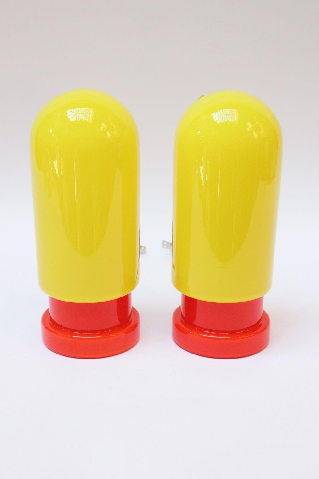 Pair of Swedish 'Capsule' form table lamps in neon yellow and red/orange blown glass (ca. 1960s).
Blend well with post-modern and mid-century modern decor, alike. 
Excellent, vintage condition with the original Swedish stickers still intact. Newly