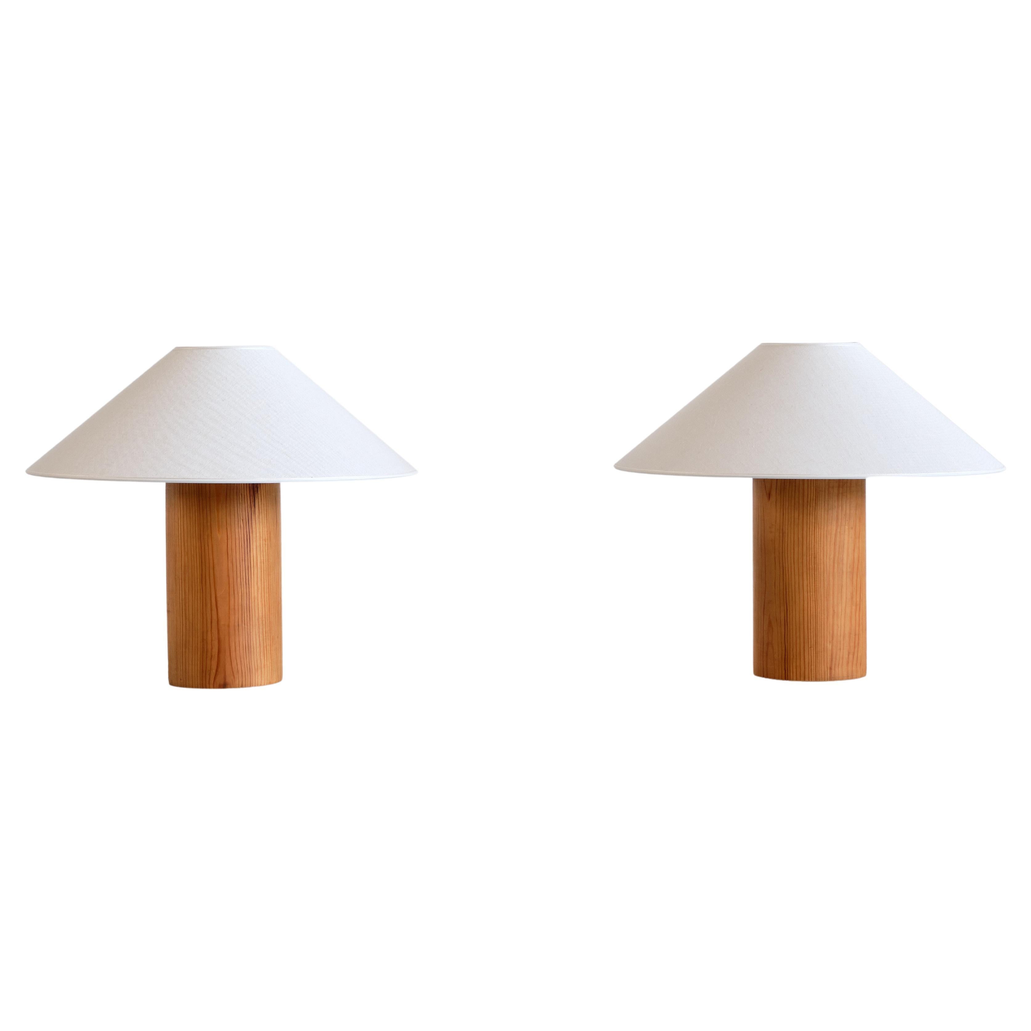 This striking pair of table lamps was produced in Sweden in the 1960s. The minimalist, clean designs consists of a cylinder shaped base in solid pine wood. The coolie shaped lamp shades have been renewed in a white, textured fabric.

The lamps