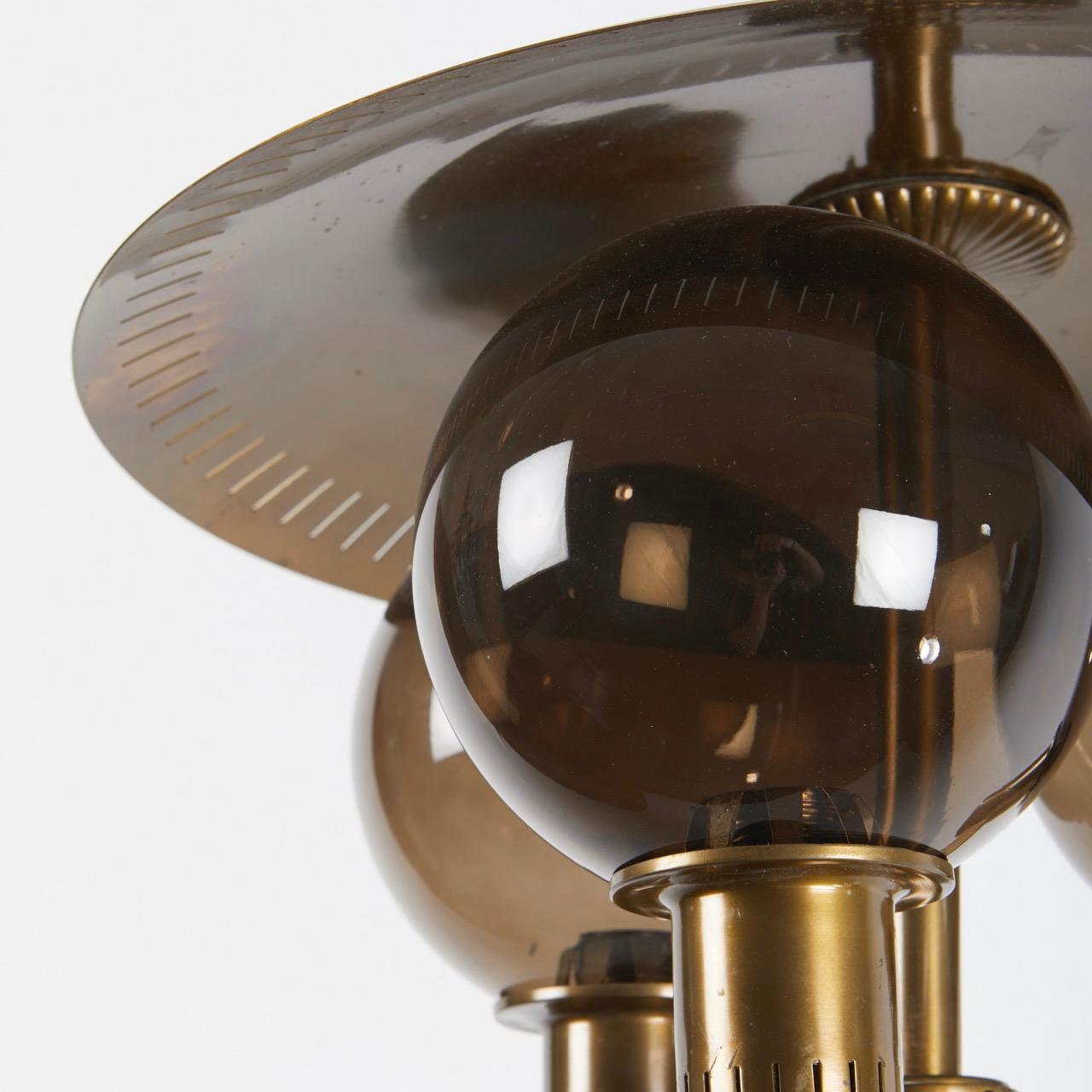 A pair of Swedish modern ceiling lights, the three smoked glass globes with brass fittings having pierced brass domed elements above shades. Circa 1970s. Includes new UL wiring