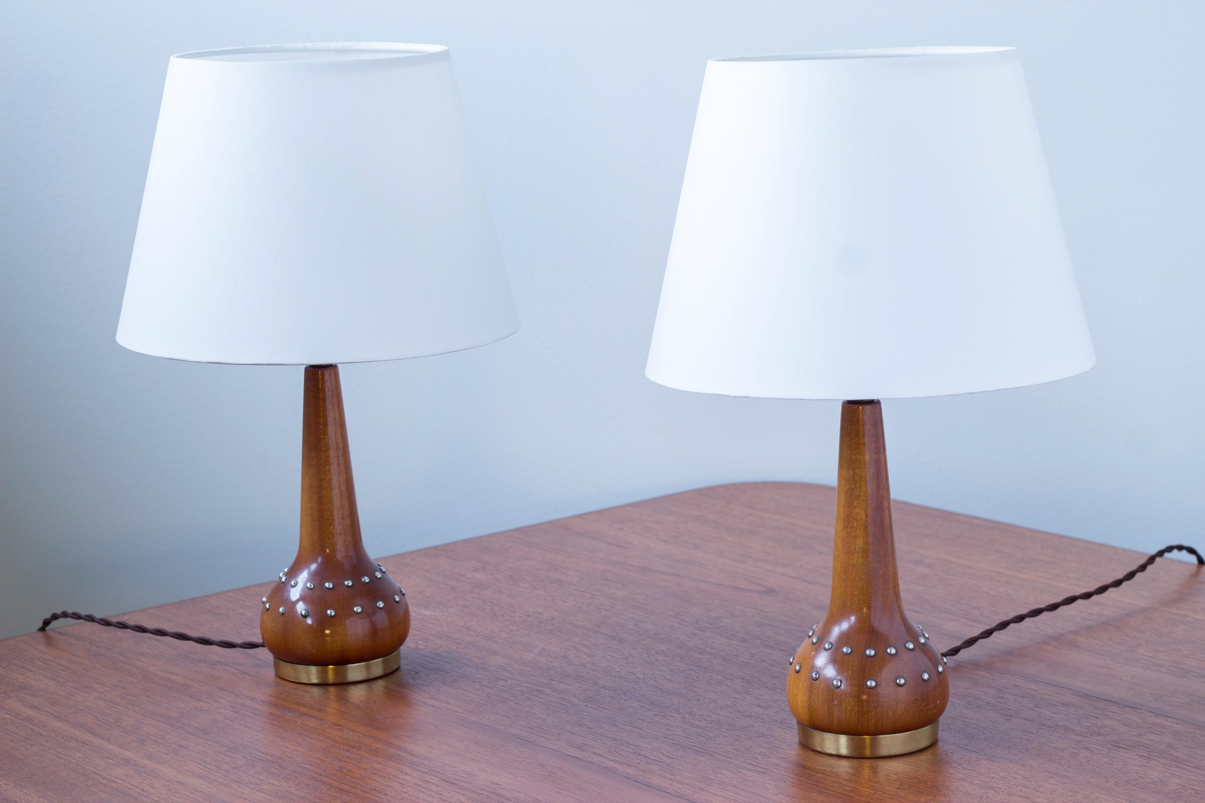 Coppia di tavolini in mogano massiccio e decorazione di chiodi in ottone intorno alla base della lampada nello stile di Otto Schulz. Realizzati con la sua tecnica brevettata 