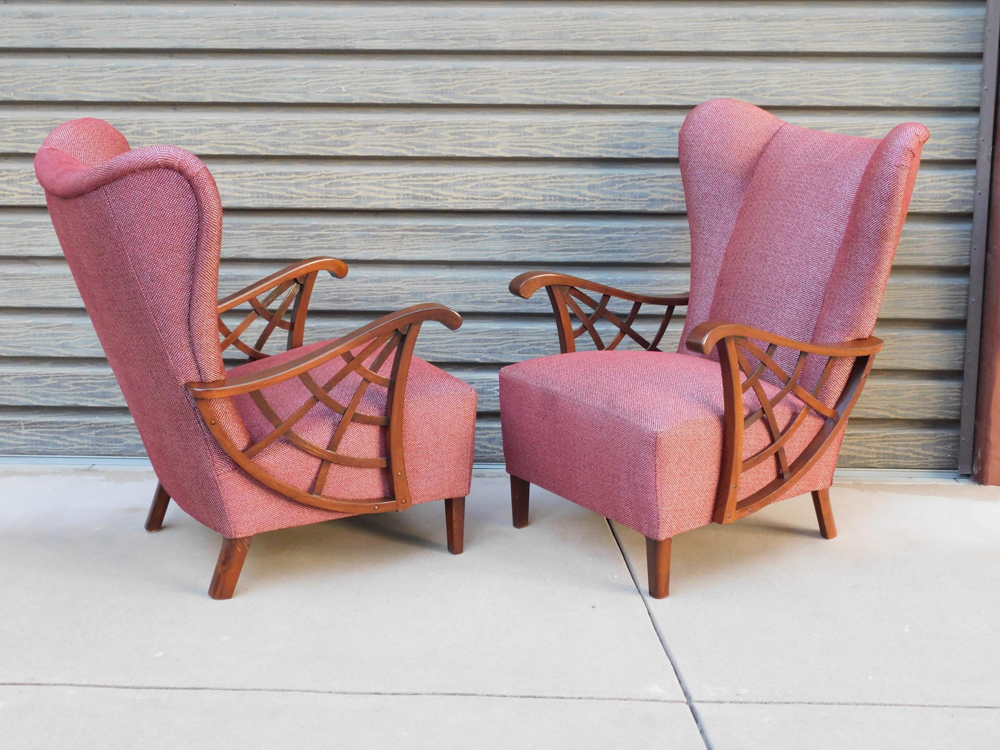 Pair of highly unusual Swedish winged back upholstered armchairs. Covered in burgundy and silver cotton/chenille. With spider web arm detail in stained elm. Completely restored and reupholstered by our craftsmen and ready for a life time of good use.