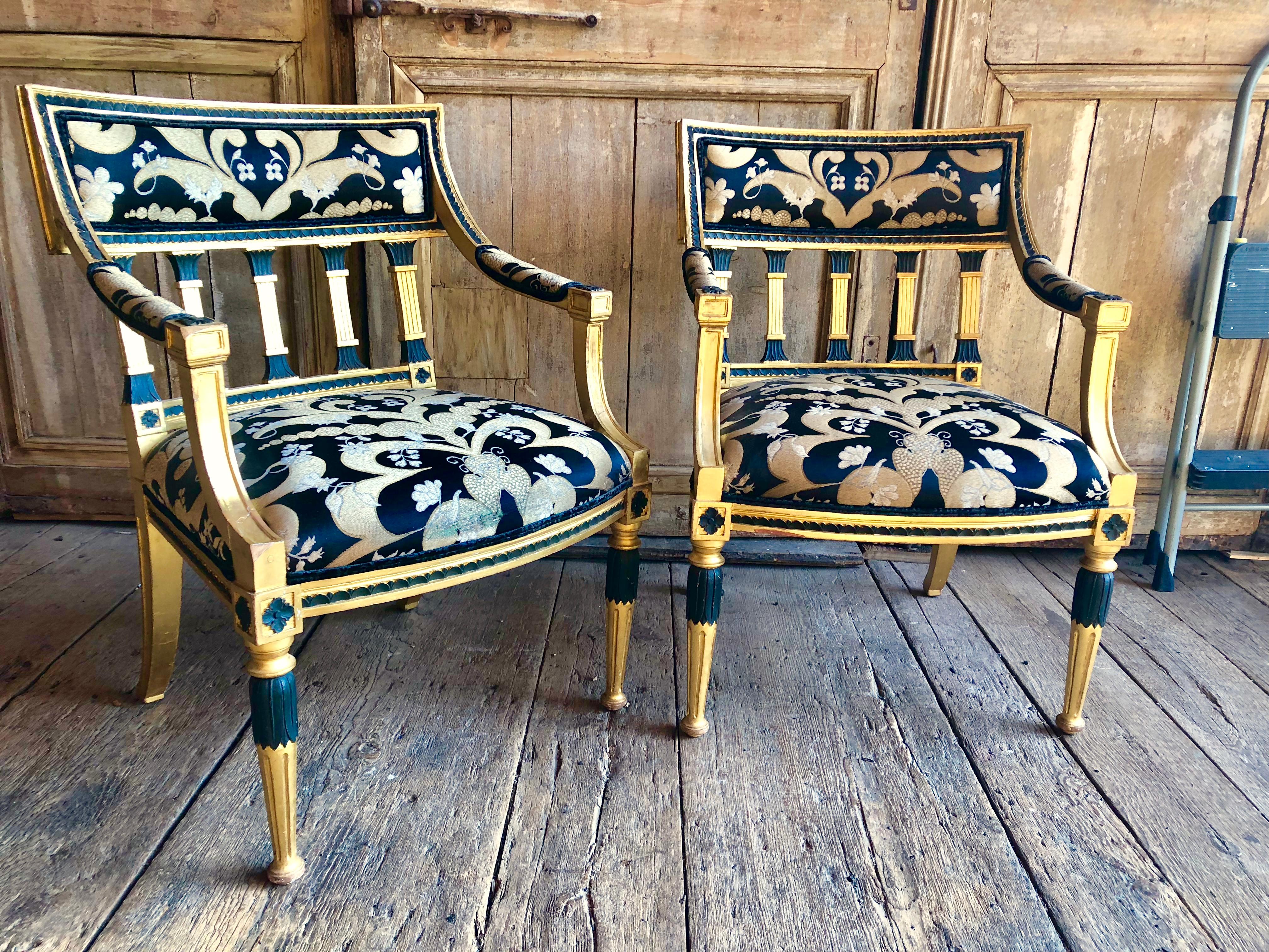 A pair of Swedish giltwood Armchairs in the neoclassical manner, late 18th/early 19th Century, with black painted accents, the back and seat upholstered in gold, cream and black silk needlepoint fabric (wear to front edge of fabric on one seat).