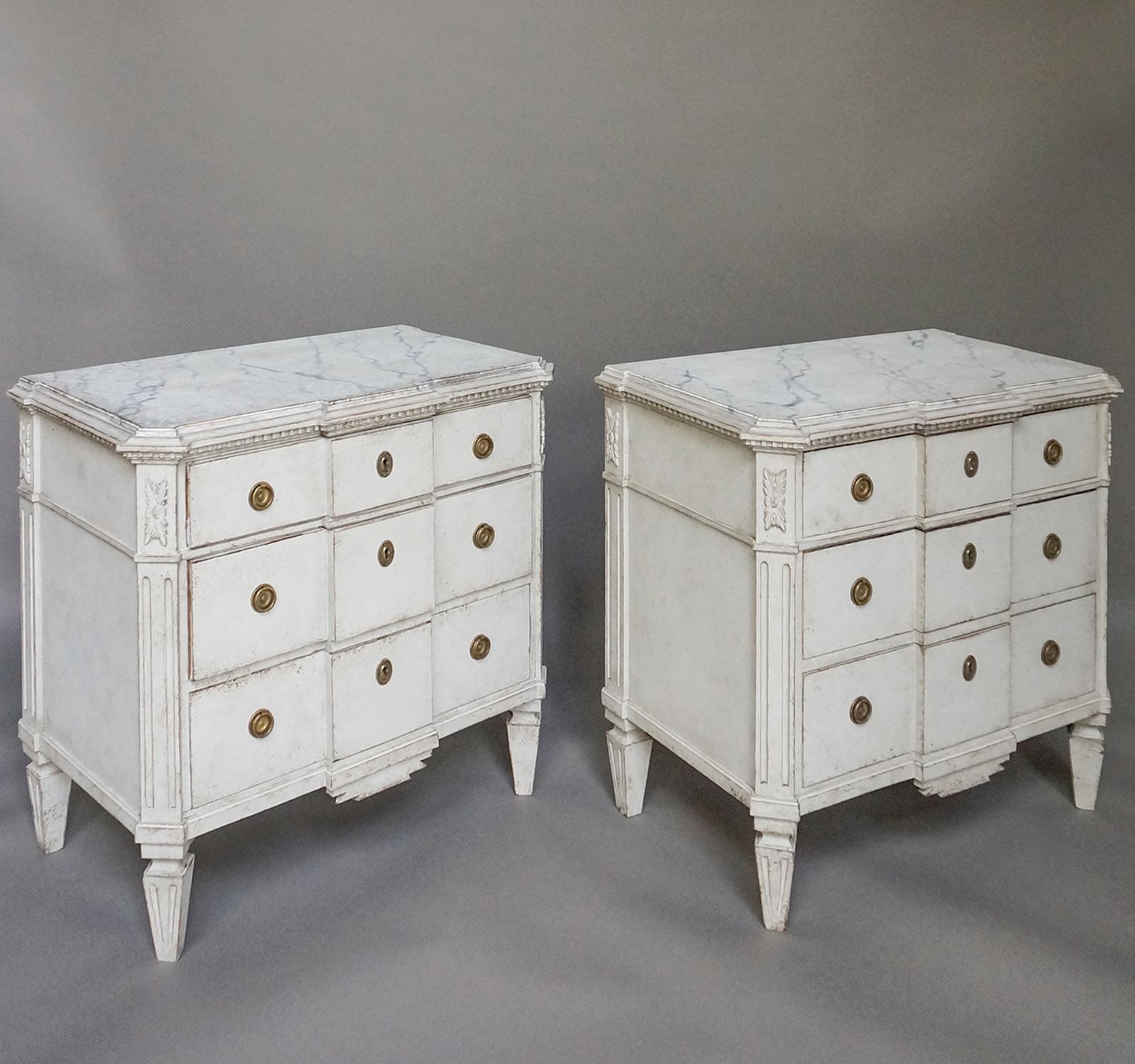 Pair of neoclassical style commodes, Sweden, circa 1910. The shaped tops are painted with a faux marble design and have finely carved dentil trim. The canted corners have applied foliate carvings above reeding that extends to the tapering square