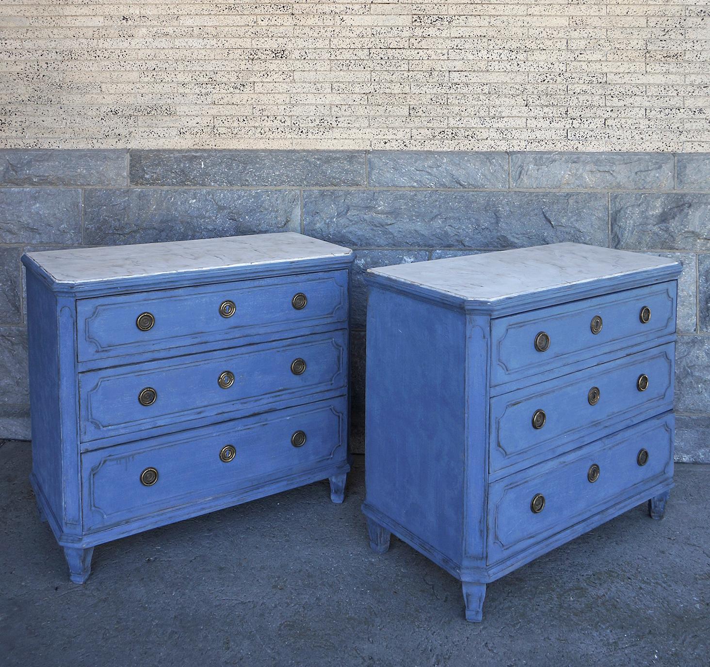 Pair of Swedish chests of drawers, circa 1860, having shaped and marbleized tops over three graduated drawers in a case with canted corners with raised detail. The drawer fronts have incised rectangles and brass hardware. The feet have been replaced.