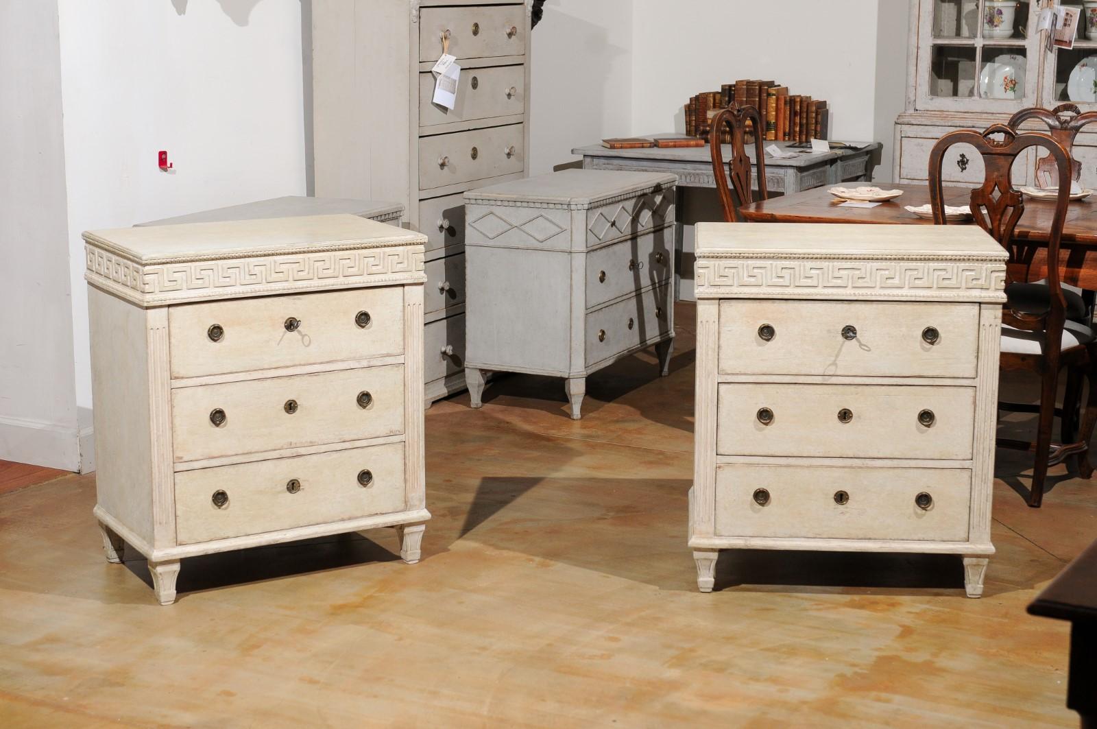 A pair of Swedish neoclassical style painted chests from the 19th century, with Greek Key friezes and fluted side posts. Created in Sweden during the 19th century, each of this pair of neoclassical style chests features a rectangular top sitting
