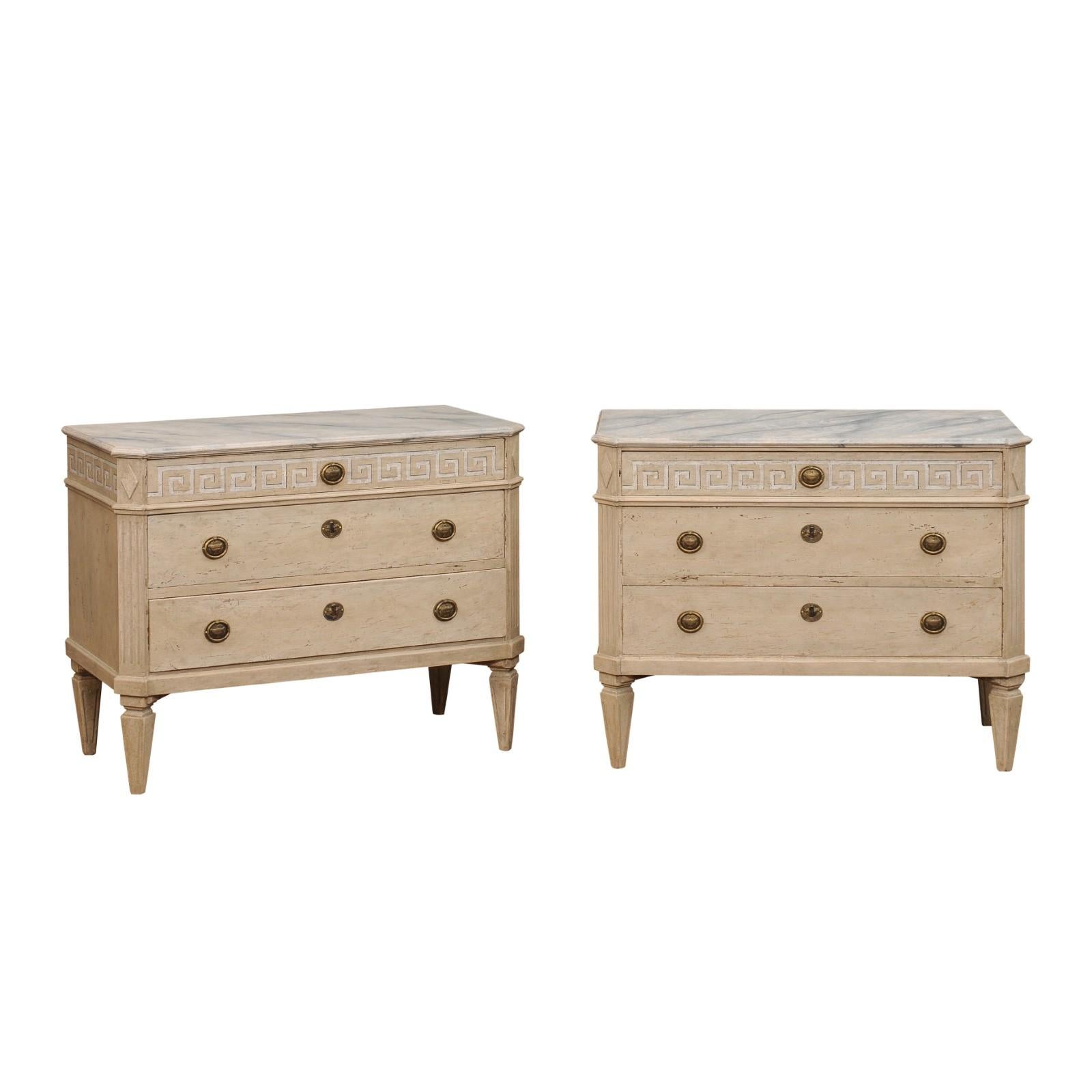 A pair of Swedish Neoclassical style chests from the 19th century with marbleized tops, painted Greek Key friezes and three drawers each. Indulge in the timeless allure of Swedish design with this pair of 19th-century Neoclassical-style painted wood
