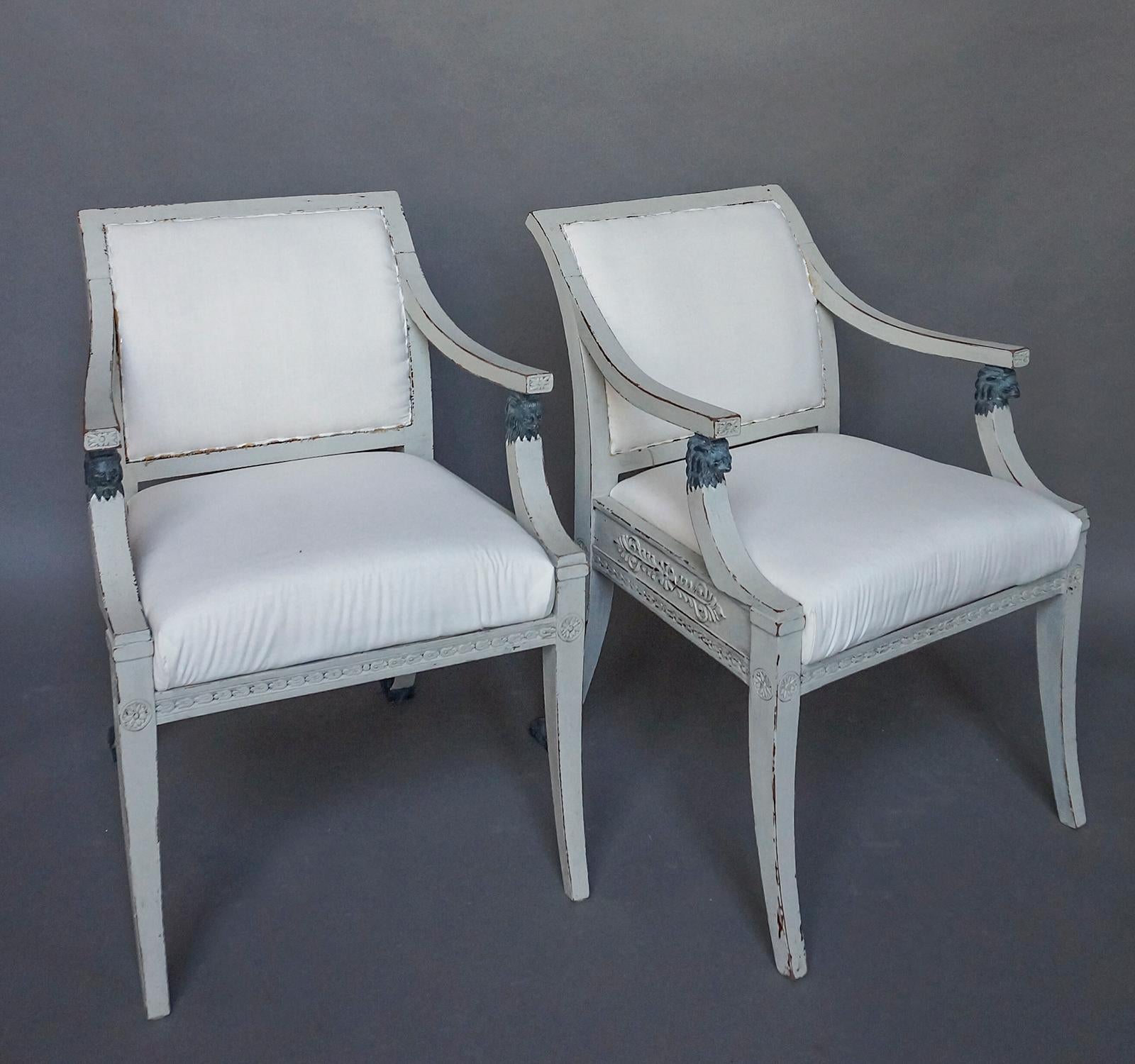 Pair of Swedish armchairs in the neoclassical style, circa 1900. The sides and backs of the frame have acanthus leaf carvings, and the arms are supported by lions’ heads. The rear saber legs terminate in paw feet. Upholstered backs and slip seats.