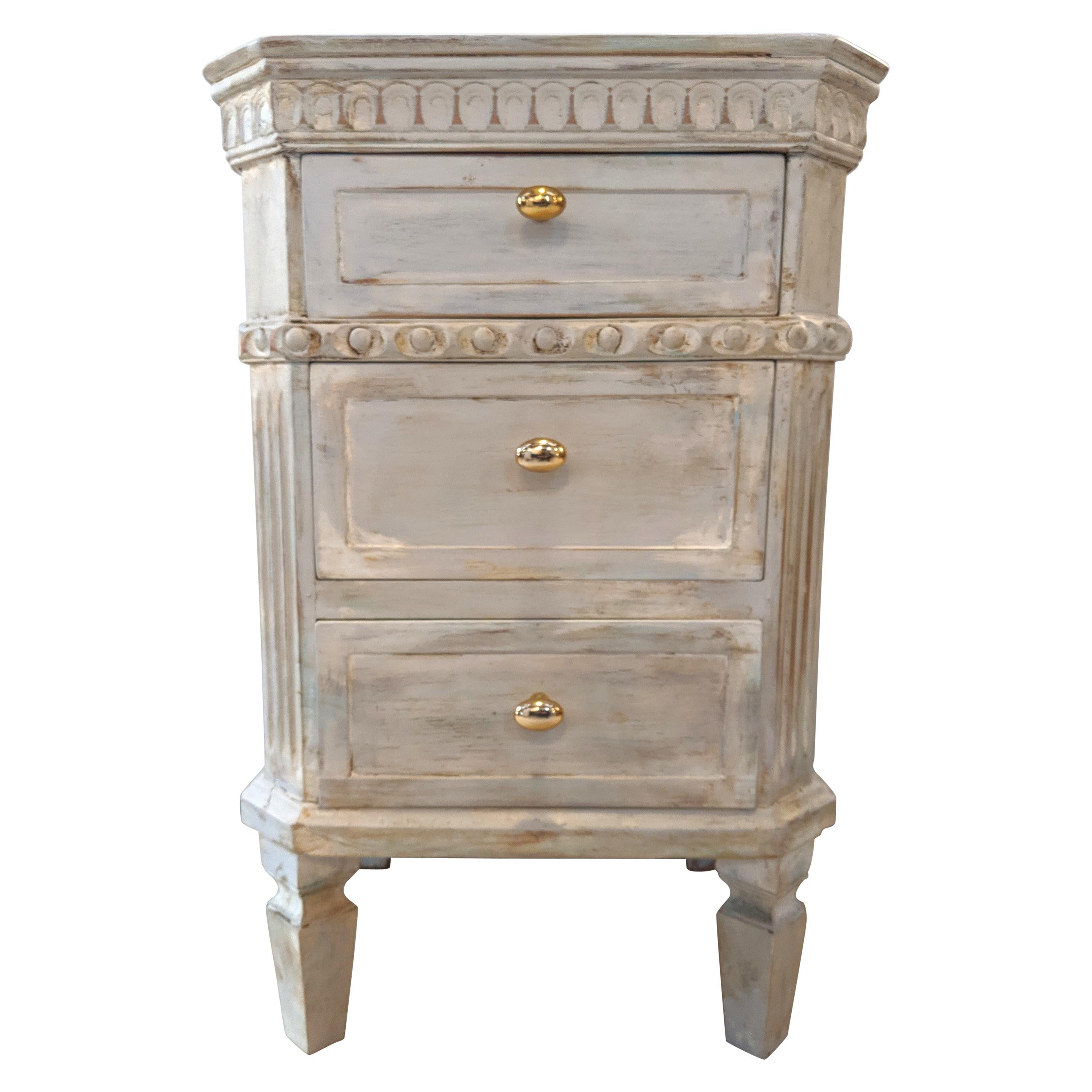Pair of Swedish paint decorated end tables or nightstands. Each made from painted distressed wood with three drawers under carved apron tops and sitting on tapering legs. The drawers with brass pulls.