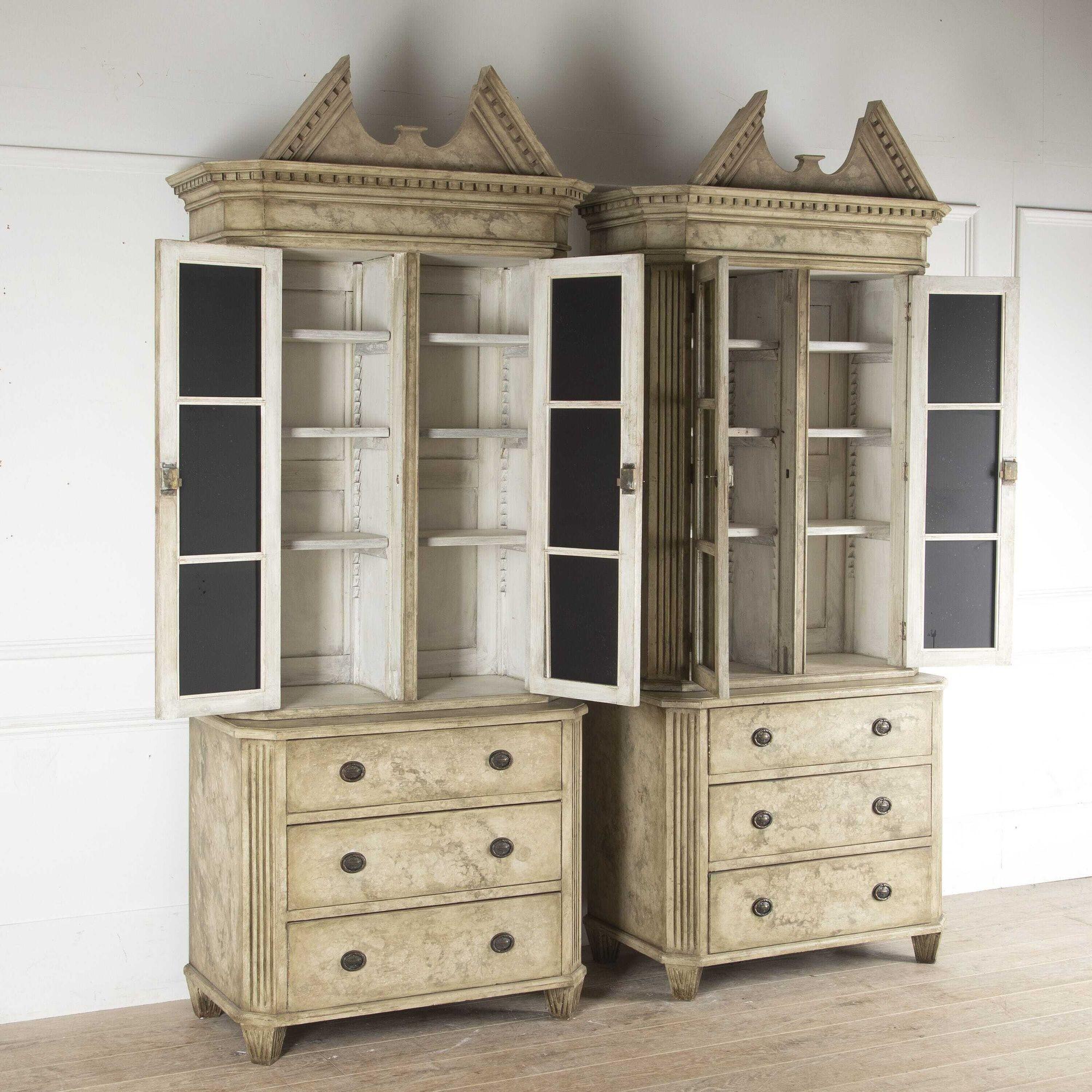 Pair of Swedish broken pediment bookcases, in painted pine. 
Although these bookcases embody the Gustavian style, they were made in the 1950s to adorn the library of a Swedish castle and match a similar antique pair. 
The top half of each is