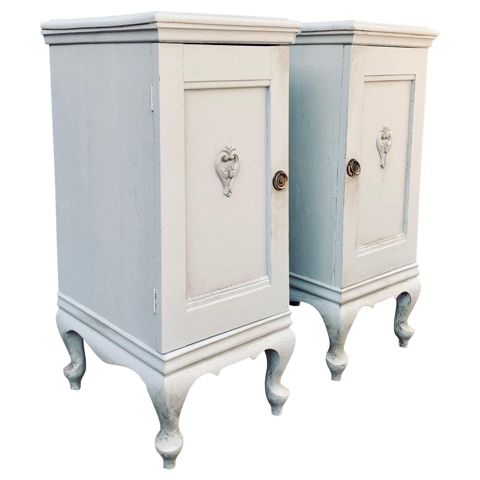 A pair of Rococo style light Gustavian grey-painted Swedish nightstands or night tables from the first half of the 20th Century. These Scandinavian have a  charming patina have each one door with matching brass handles and a shelf on the inside.