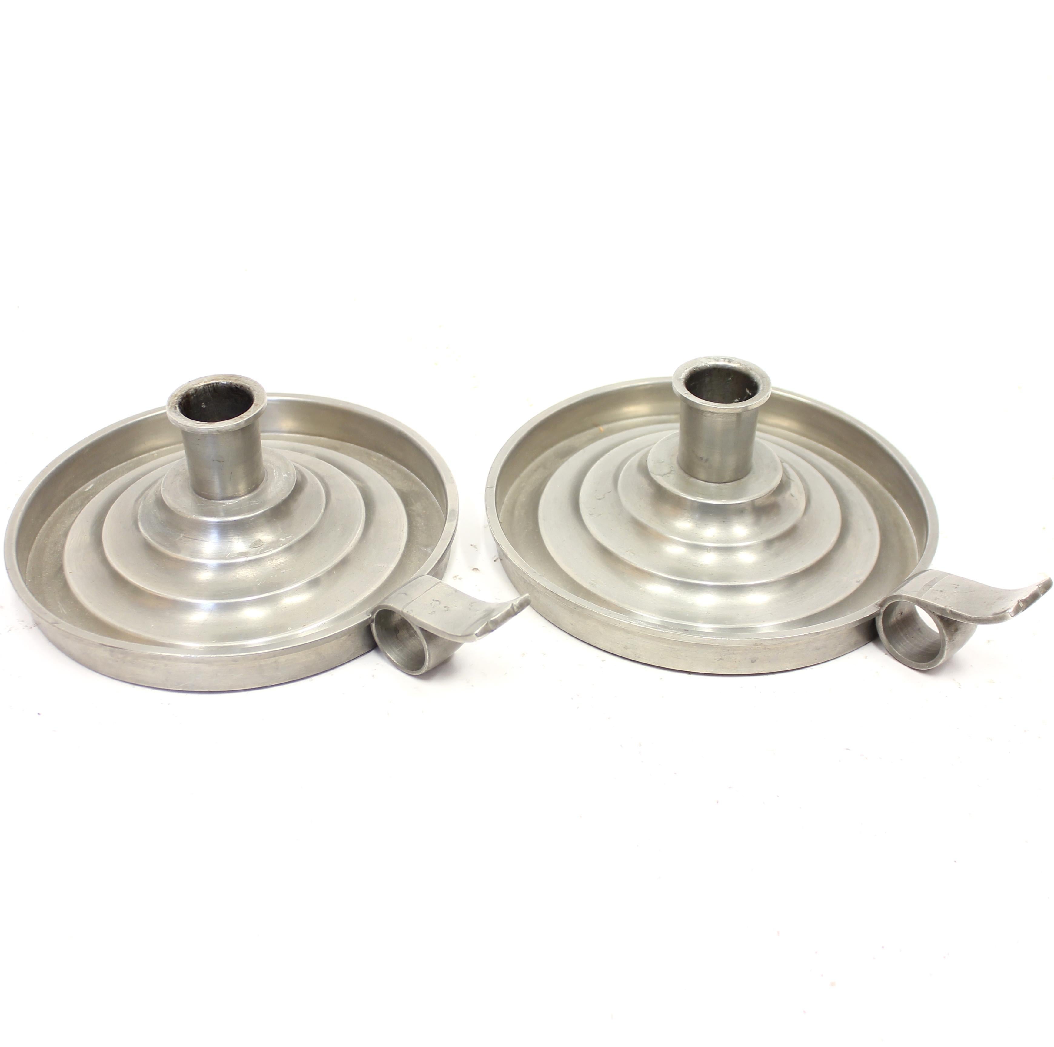 Pair of Art Deco candle holders manufactured by Swedish firm C.G Hallberg from the 1930s. Round form with a stepped inner section that holds up the candles in the middle. Handle on the side for easy carrying. This kind of small candle holders with a
