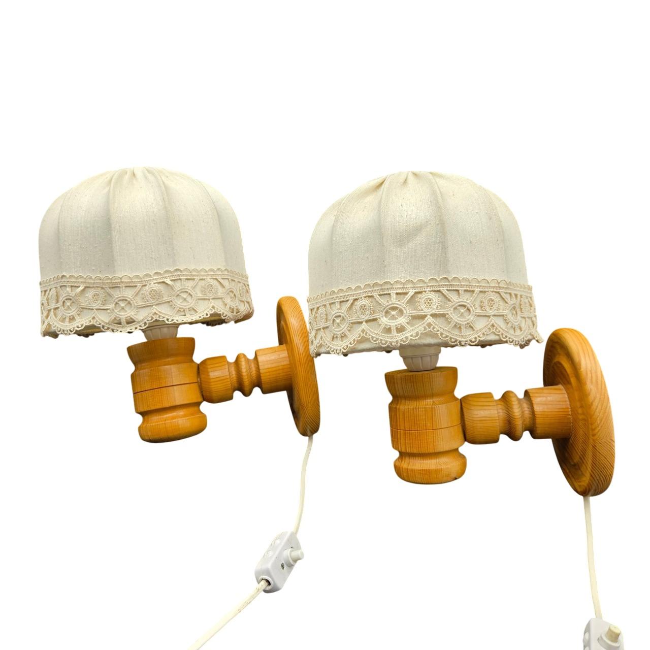 Magnifique paire d'appliques scandinaves fabriquées en Suède dans les années 1970. Ces lampes présentent des bases en bois de pin massif tournées à la main dans un ton miel chaud, mettant en valeur le savoir-faire artisanal typique du design suédois