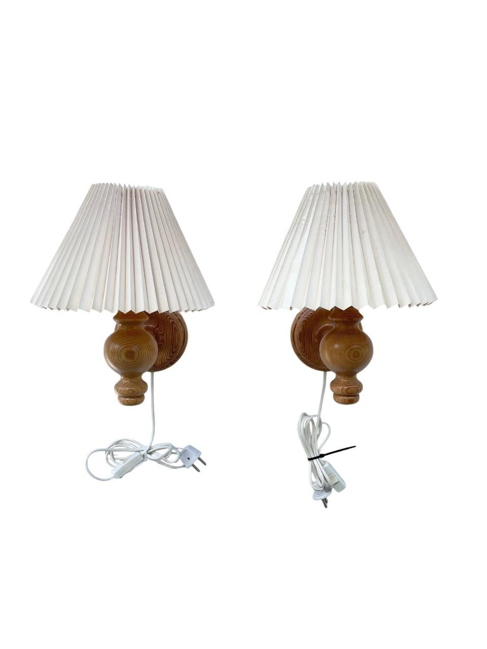 A charming pair of handcrafted Swedish wall-mounted lamps made from solid pine wood, dating to the 1970s. These sconces feature beautifully turned wooden arms and backplates, exhibiting the natural grain of the pine. Each lamp is topped with a